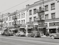April 1942. "Los Angeles, California. Street scene in Little Tokyo." Businesses represented here on East First Street include the Hotel Mikado, Sho-Fu-Do confectionery, Ten-Gen restaurant, Sato Book Store, Hotel Empire, Sumida & Son hardware, Angel Cake Shop, Moon Fish Co., Eagle Employment Agency, Kawahara Co. and Dr. C.K. Nagao, dentist. Medium format acetate negative by Russell Lee for the Office of War Information. View full size.