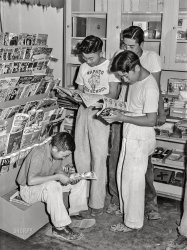 July 1942. "Nyssa, Oregon. Japanese-American boys at the newsstand on their weekly visit to town." Acetate negative by Russell Lee for the Office of War Information. View full size.
Not at our hometown newsstand --As soon as we kids grabbed a comic book, Margaret the Miserable would swoop in on her broom and out the door we went. There was NO reading without buying.
You Learn Something New Every DayOK, I've never heard of Napoleon and Uncle Elby, but apparently it was popular in newspapers and comic books of that era. In fact that is issue No. 1 in the rack.
Hey, look!The August issue of Railroad Magazine is out! 
Back in the dayI remember "looking through" Sixteen magazine and all the others on the rack, when we were allowed to browse. Just as these fellows are doing.  Today magazines are enclosed in wrap to prevent this.  I miss the slower times.
Home of the Wapato WolvesLess than 1,000 students for three grades today.  Colors are blue &amp; gold.  It appears they use two wolf images for their mascot.  The scary version on the young man's t-shirt, and a more regal image for when they're not trying to be an animal and rip the other team apart.
I sold what was left of my comic book collection a little over a decade ago.  I had lots of the action heroes, plus Archie and Mad Magazine.  I was surprised the comic that brought the highest amount was Rocky the Flying Squirrell and Bullwinkle ... $25. As with so many things I've purged, I'm glad they found a good new home.  The closet they were stored in recently flooded.
Somber ReadingIt would have been hard for those Japanese-American kids to view some of the racist depictions of our Pacific enemies that were so prevalent in comics of the war years. It may have seemed right to most at the time, but it still must have hurt those young minds.
So Few Comics?Leaving aside all the pulp fiction, detective and romance magazines, and general magazines, I only see three comic books:
-- Captain Aero #8 September 1942 “Keep ‘em Flyin!” Introduces the Red Cross.
-- Walt Disney’s Comics and Stories Vol. 2 #11 August 1942 (#23)
-- Napoleon and Uncle Elby #1 1942
If only the kids knew. Current values in mint condition, respectively:
over $1,000
over $2,050
over $700
... not bad for a 10 cent investment.
Freedom from fearRe: Nyssa, Oregon detention facility for Japanese-Americans see https://encyclopedia.densho.org/Nyssa,_Oregon_%28detention_facility%29/
Napoleon and Uncle Elby comic books consisted of reprints of the newspaper strip. https://en.wikipedia.org/wiki/Napoleon_and_Uncle_Elby
Issue #1 (pictured) was published in 1942
So that&#039;s where they went.My grandfather owned and operated an apple ranch in Wapato, Washington,
near Yakima, 300 miles from Nyssa.  He often told us that his best orchard
workers had been people of Japanese ancestry.  These people suddenly
disappeared in the spring of 1942, and never returned to the Yakima Valley.
(The Gallery, Kids, Relocation Camps, Russell Lee, Stores & Markets)