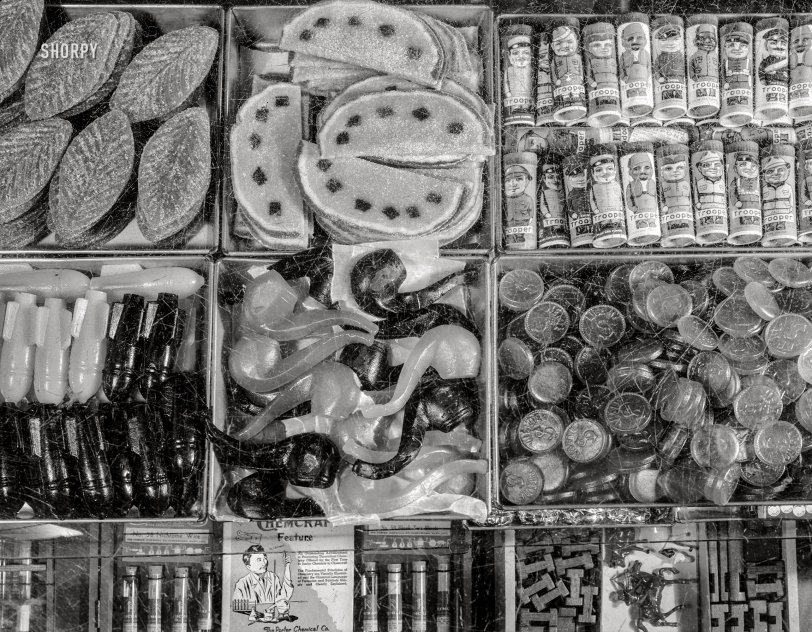 This uncaptioned but intriguing entry from among the many photos taken by John Collier in and around Washington in January 1942 has his Speed Graphic pointed down through the top of a well-worn display case bearing a bounty of candy (Troopers, anyone?), chemistry sets (Porter "Chemcraft") and a miscellany of small toys. 4x5 inch acetate negative. View full size.
