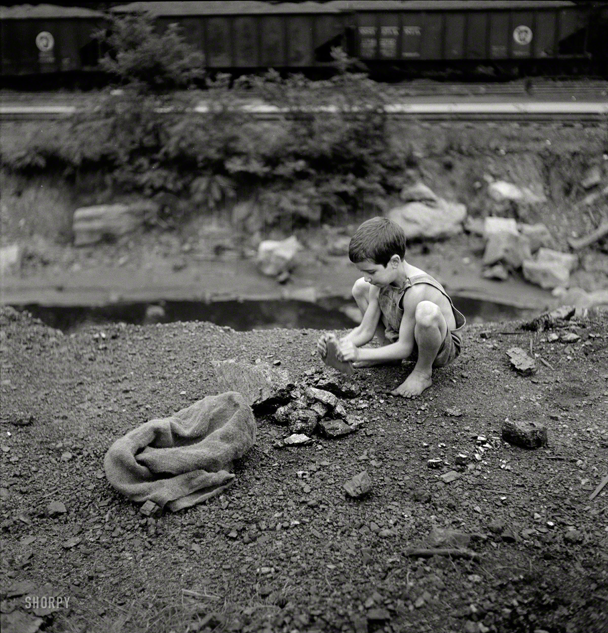 September 1938. "Coal miner's child breaking up large pieces of coal to take home. Pursglove, Scott's Run, West Virginia." Photo by Marion Post Wolcott for the Resettlement Administration. View full size.