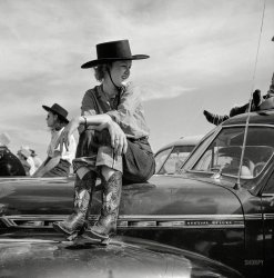 September 1941. "Dude at rodeo in Ashland, Montana." Whose ponies are all under the hood. Medium format negative by Marion Post Wolcott. View full size.
Tough in the HoodRemember those old cars where you could actually sit on the hood without leaving a dent?
Dude?I think she's a Dudette!
[That's "dude" in the sense of a non-cowboy of either gender dressed up in faux-cowboy fashion. Hence "dude ranches" that catered to city slickers. -tterrace]
Boots Dudette -- get those boots off my fender. Even if it is big enough to be a dance floor.
Girls on the HoodThe Good Old Days neatly defined: The people were thinner, the metal was thicker.
Paint, not so muchYes, the metal was thick and tough (which was why the car weighed 4000 lbs and had the overall agility of a dump truck) and transferred crash energy to the "crumple zone" AKA the driver and passengers!
   But seeing the girl on it doesn't make me think of the metal, it makes me look at the paint. She's scratching the heck out of it. And that way some sort of lacquer, which is absurdly fragile compared to modern paint. At least it's easy to fix.
[For the record, a 1941 Chevrolet Special Deluxe weighed about 3,200 pounds. A 2015 Chevrolet Impala tips the scales at 3,800. - Dave]
Very fashionableHer jeans are made from expensive and highly sought after selvedge denim (you can tell by the seam edge where she has them turned up); common in those days - fashion buzz word in 2015.
(The Gallery, Cars, Trucks, Buses, M.P. Wolcott)