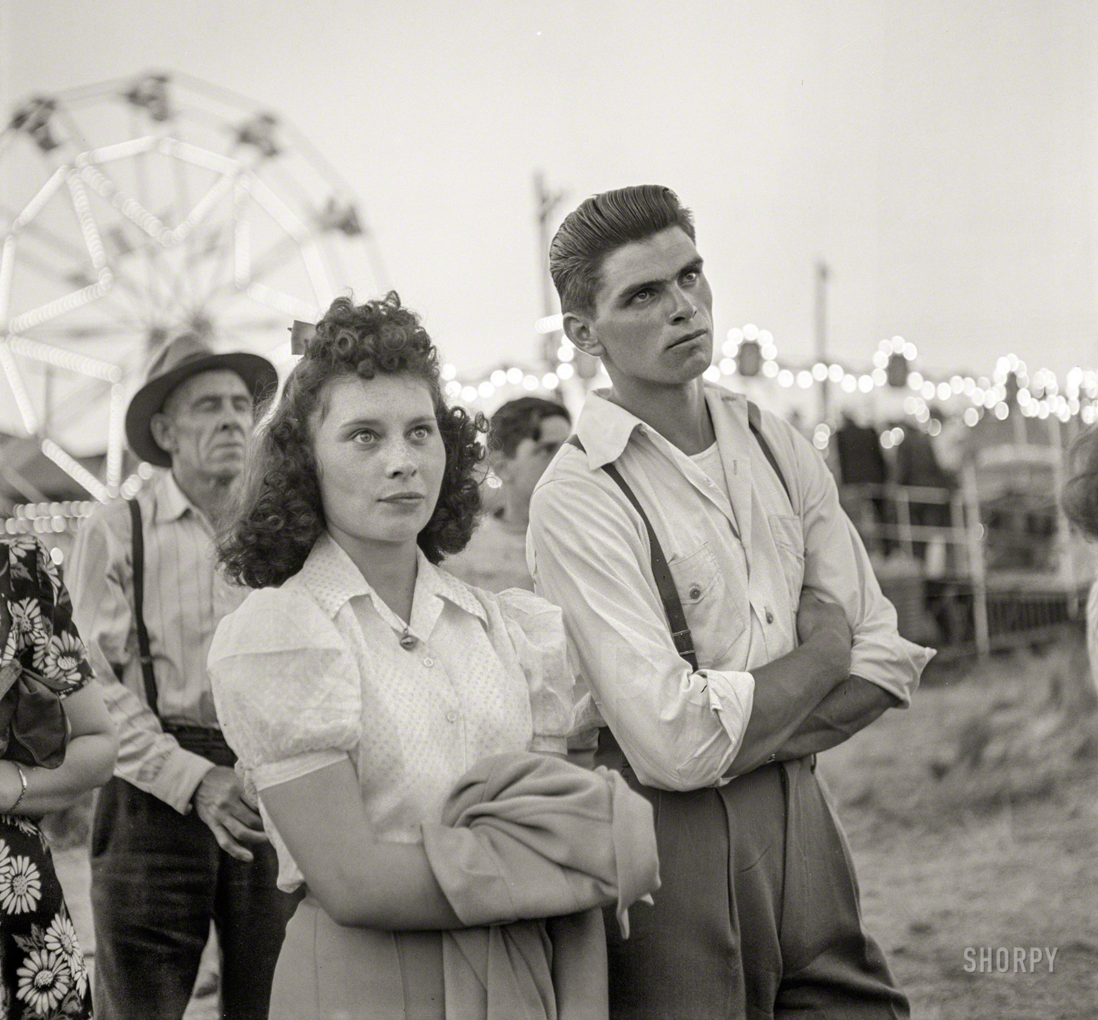 July 1942. Klamath Falls, Oregon. "At the sideshow of the circus." Step right up, folks, and SEE the pop-eyed girl! For a paltry dime, BEHOLD the Serious Boy! Photo by Russell Lee for the Office of War Information. View full size.