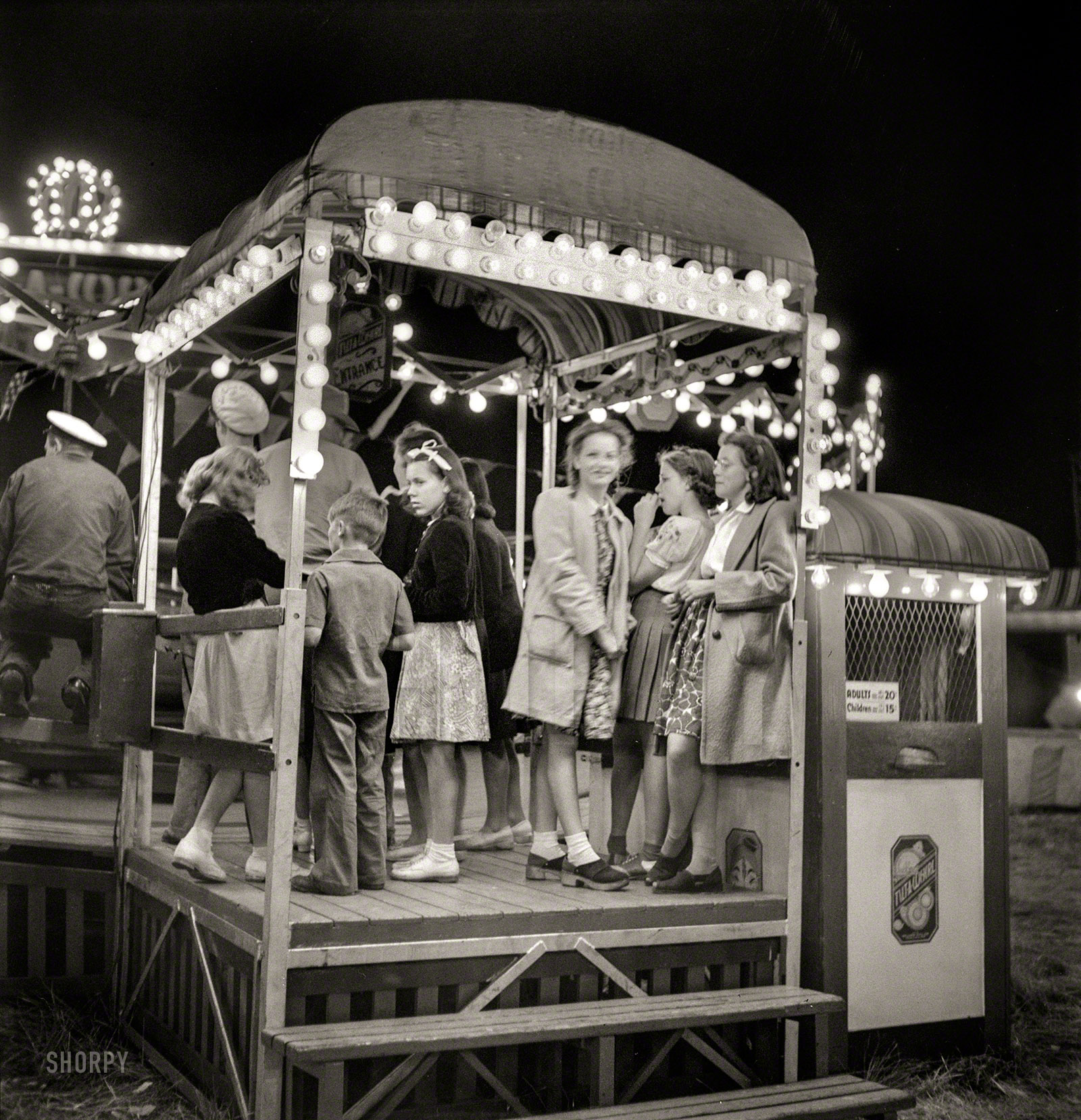 July 1942. "Klamath Falls, Oregon. Carnival of the circus." In line for the Tilt-A-Whirl. Photo by Russell Lee for the Office of War Information. View full size.