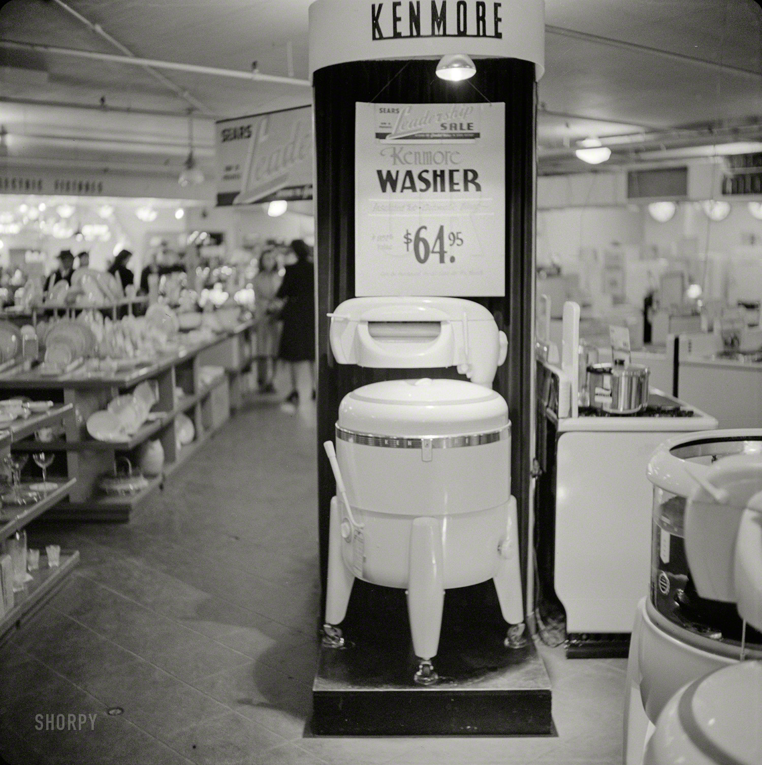 &nbsp; &nbsp; &nbsp; &nbsp; Its big 8-sheet porcelain tub is insulated to keep water warm! Streamlined 8-position wringer with soft balloon rolls has chromium pressure controls; push-pull safety release; roll-stop safety dry feed rest and automatic water-return board.
October 1941. "Kenmore washer for sale. Sears Roebuck store at Syracuse, New York." Medium format negative by John Collier. View full size.
