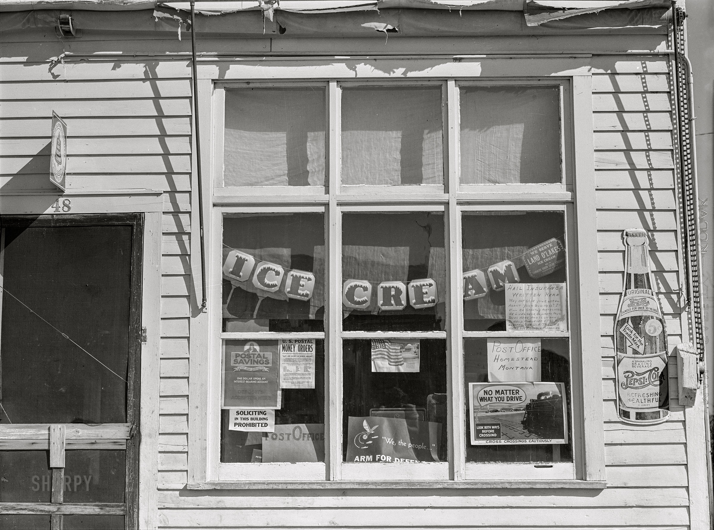 August 1941. "Window of post office and store in Homestead, Montana." Medium format negative by Marion Post Wolcott for the Farm Security Administration. View full size.