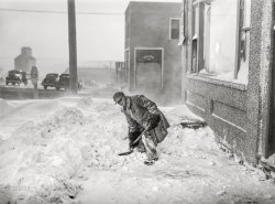 November 1940. "Shoveling snow. Draper, South Dakota." Medium format acetate negative by John Vachon for the Farm Security Administration. View full size.
Looks like the Siege of StalingradBut that's still two years in the future.
Oh, my aching back!Clearing snow with a short-handled shovel is a surefire way to throw your back out. 
I never thought I&#039;d say thisI hope that's mold on his face and not snow!
Any bets --The next plow that comes through will throw that snow right back on the sidewalk.
Still there (2019)
Sign of the timesI had forgotten that stop signs used to be yellow, not red. But I have not forgotten the blizzards out in open country - it's the wind, the constant wind.
November, 1940And still clearing the snow from last May.
(The Gallery, John Vachon, Small Towns)