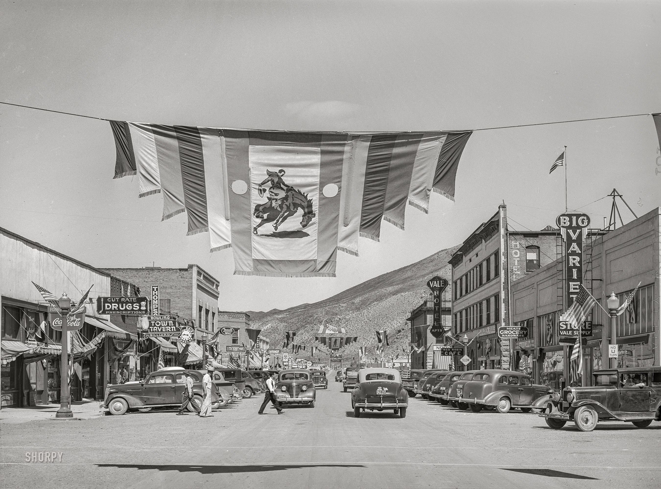 July 1941. "Main street of Vale, Oregon, on the Fourth of July. Vale is one of the shopping centers for farmers who live and work on the Vale-Owyhee irrigation project." Medium format acetate negative by Russell Lee for the Farm Security Administration. View full size.