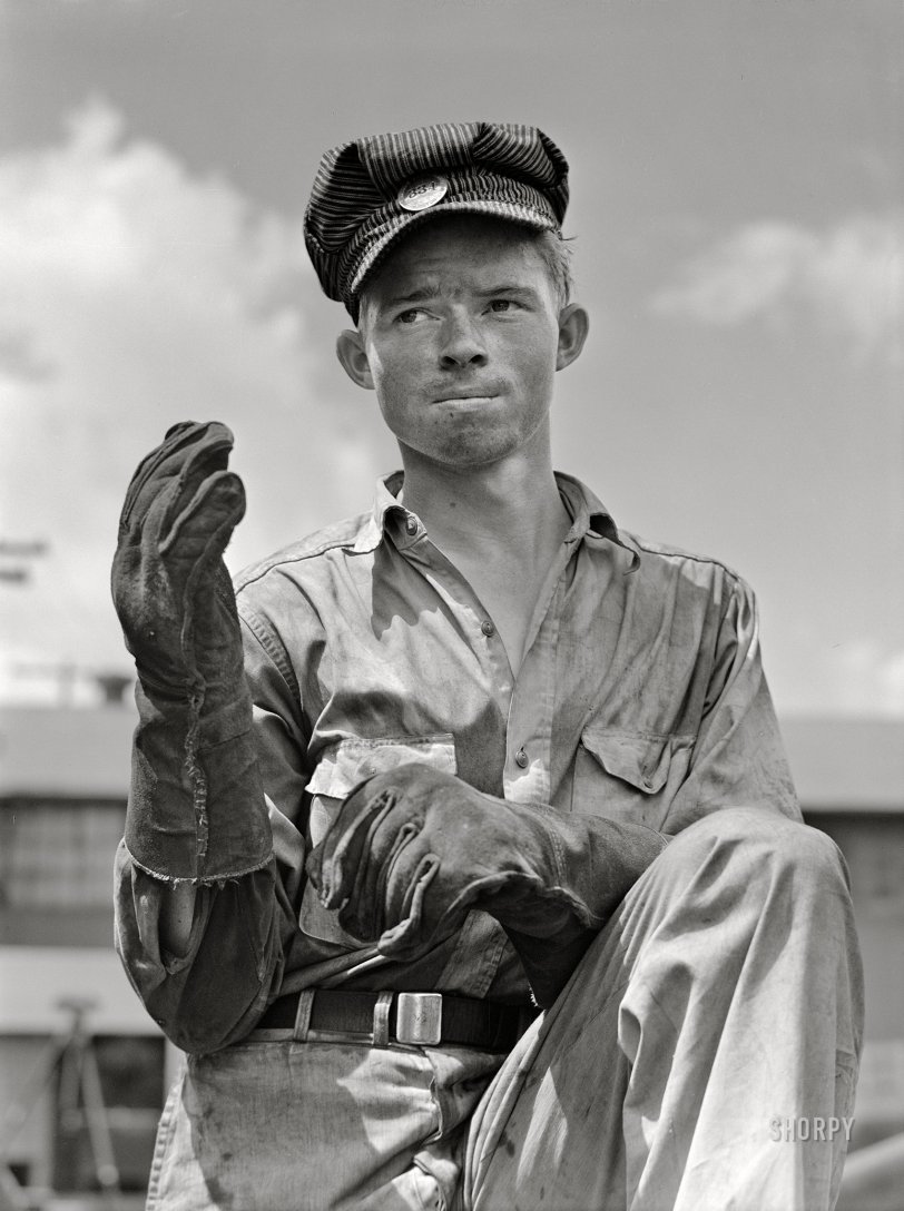 July 1942. "Decatur, Alabama. Ingalls Shipbuilding Company. Construction of ocean-going barges for the U.S. Army. Welder's helper shading his eyes from the welder's torch." Acetate negative by Jack Delano for the Office of War Information. View full size.