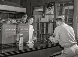 September 1942. "Fort Belvoir, Virginia. Sergeant George Camplair on one of his many visits to the post exchange." Acetate negative by Jack Delano, Office of War Information. View full size.
Many Visits?Who can blame him?
Born here ...Eight years later, I was born at Fort Belvoir, as Walter Reed was full up. They did not give me a softie cone, though. Just a slap on the behind.
I can see whyI also would be making as many visits to the PX as my duties would allow, with a doll like that behind the counter. Woof!
Yes Sir!I can see why the sarge is a frequent customer and it ain't because of the cold fountain drinks or the Chesterfields.
Nutty for McNuttThe woman here with Sgt. Camplair in 1942 looks to be Mary Jane McNutt, co-worker bride per that 1946 wedding post found under his onion peeling pic.  
“Many visits to the post exchange” indeed, thus making it two winning campaigns for the duration.
Hmmm ...One has to wonder if this is also a picture of the future Mrs. Camplair. 
Same uniform for me The cap I have still fits. The rest just didn't keep pace. 
Whatcha got there, soldier?I can read the word Exchange and understand it's base currency.  Not sure how much they pay a sergeant for peeling onions.  I can't find an example of it on the Internet.

Camblair?Hi Dave, 
The name is spelled Camblair according to Library of Congress. Love the photo, BTW.
[Camplair, with a P, is the correct spelling of his name. - Dave]
They treat you right?The surgeon general will disagree in a little over 20 years, but it is a cool advertisement by Chesterfield.
(The Gallery, Eateries & Bars, Jack Delano, Pretty Girls, WW2)