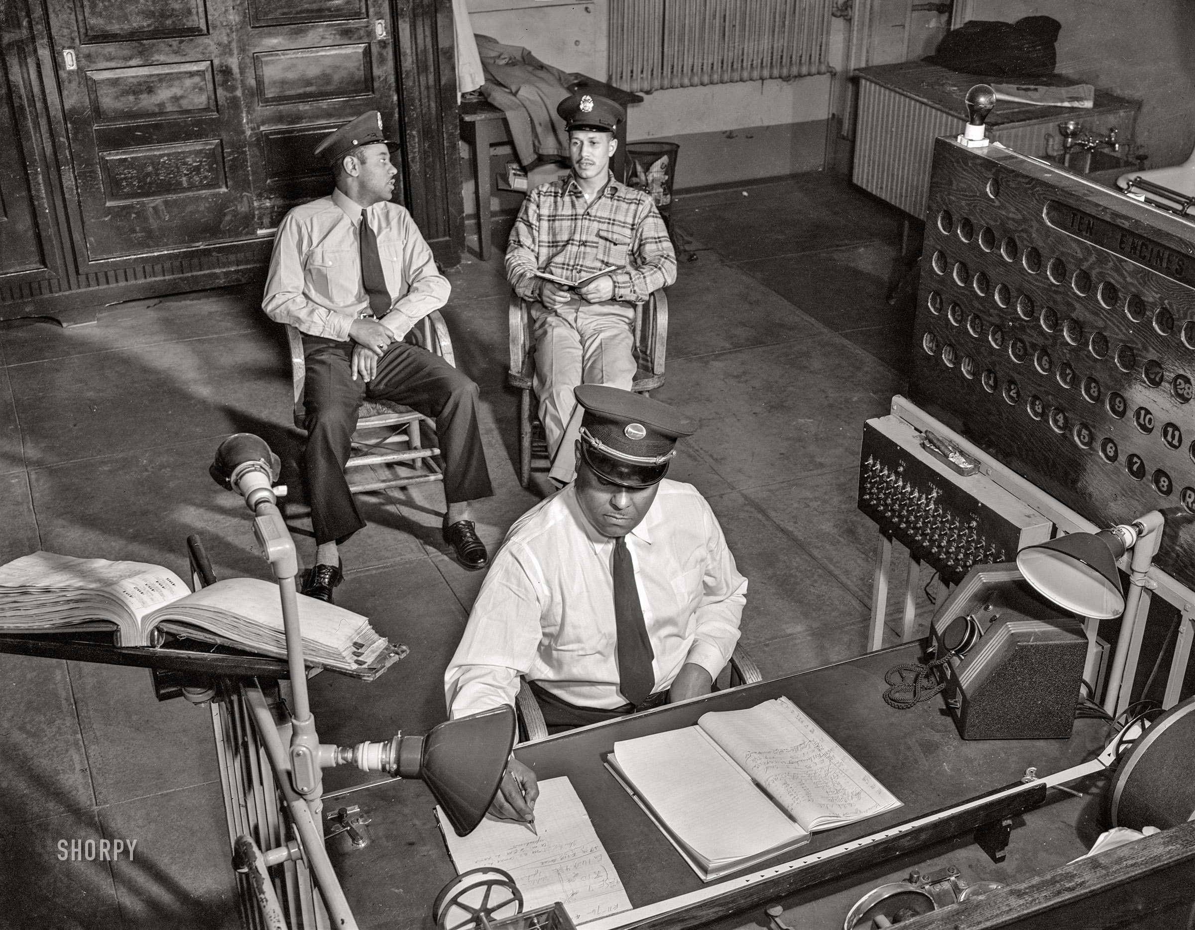 January 1943. Washington, D.C. "Firehouse Station No. 4, one of the separate Negro units in the District. Lieutenant Mills on duty at the alarm desk. Two firemen in the rear quiz each other on the quarterly examinations they must take during their probation period." Acetate negative by Gordon Parks for the Office of War Information. View full size.