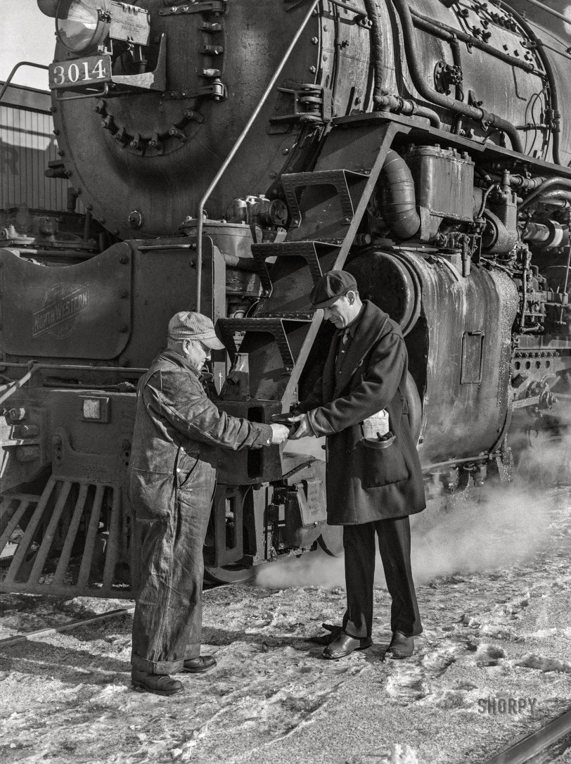 January 1943. "Conductor handling engineer copy of train orders before a Chicago and North Western freight pulls out of Chicago for Clinton, Iowa. Since the track between those points is under automatic train control, the engineer hands the conductor the key to the automatic train control lock of the engine. The conductor will keep the key in the caboose until the train arrives at its destination." Acetate negative by Jack Delano, Office of War Information. View full size.