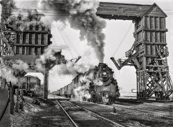 January 1943. "Nelson, Illinois. Chicago and North Western Railroad freight en route from Clinton, Iowa, to Chicago. Stopping for coal and water to give passenger trains the right of way." Acetate negative by Jack Delano for the Office of War Information. View full size.
Great shotThe wooden towers and skywalk look so Dickensian. Such an awesome pic.
Still chuggin&#039; (in model form)A limited production run of O scale models of CNW Baldwin 4-8-4 3016 was released back in 2012  for around $1400 a copy http://www.pwrs.ca/view_product.php?ProductID=200150
The wooden coaling tower at Nelson IL was eventually replaced with one of concrete, which still stands, but the diesels that run under it today don't stop (though some may toot in tribute).
Never ceases to amaze me.The powerhouse that America was during those war years.
CoalI think the global temperature rose a degree while I looked at this image. 
Passenger trains have right of way over freights?If only we could go back to that. I can't tell you how many times I've been delayed on Amtrak outside the Northeast Corridor because the train had to yield right of way to a freight train.
C&amp;NW at NelsonThis train appears to be eastbound. The junction with the C&amp;NW's "SI" Line is back where the signals are in the distance. Going east, the train would likely take the Nachusa Cutoff to avoid the fairly stiff eastbound grade through Dixon. Nelson tower would be to the right behind the locomotive.
(The Gallery, Jack Delano, Railroads)