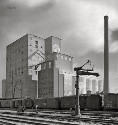 January 1943. Riverdale, Illinois. "Freight operations of the Indiana Harbor Belt Railroad. Grain elevator and mill at a siding of the Harbor Belt's Blue Island Yard south of Chicago." Medium format acetate negative by Jack Delano for the Office of War Information. View full size.
Water StopToday's photographer might use AI to remove the arm (water stop?) from the image. Or maybe not.
Perhaps the tall stack as well.
I say, leave 'em in -- they're part of the story.
A dangerous job made worseSleet or freezing rain has been the order of the day here. Everything is covered with a glaze of ice, making the easiest tasks of railroading a threat to life and limb. 
All of the railroads represented by the boxcars here are long gone.
Fallen FlagsPM Pere Marquette
CCC&amp;StL Cleveland, Columbus, Cincinnati &amp; St. Louis "Big 4"
NYC New York Central
SL-SF St Louis-San Francisco "The Frisco"
DT&amp;I Detroit, Toledo &amp; Ironton "We Have the Connections" Henry Ford's RR
It used to be fun to see how many different carriers cars were in a freight train. Now unmarked private cars (reporting marks end in X) go sliding by incognito. 
Freezing hazemade buildings in the background look as if being painted.
(The Gallery, Jack Delano, Railroads)