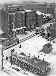 February 1942. "Lancaster, Pennsylvania." Ebby's Diner and the Corine Hotel at Queen and Chestnut streets. Photo by John Vachon for the Office of War Information. View full size.
Trolley 236 still runningLancaster had a city streetcar system and an extensive electric interurban railway service in the area. It lasted until 1947 when buses replaced the trolleys. Birney car 236 still runs in nearby Manheim, and you can learn all about it in this video. John Vachon's street views from above really capture that moment in time.
Delicious geometriesCertain photos on this website work their magic immediately and then leave me to try to figure out where the power comes from.  First to spring out at me are the pleasing geometric planes, forming a big Z in the middle, with the streetcar tracks acting as the central diagonal.  Then there’s Ebby’s Diner, which appears like a larger version of those two streetcars.  And the allure of those cozy establishments -– how I wish I could go to eat at that diner or The Village restaurant or even Sprenger’s, whatever kind of place that is.  And winter!  Bravo, John Vachon.
Here and GoneThe diner is gone. It would have been to the far right facing Chestnut. The hotel is gone too. It would have been where the parking lot is now. The three-story brick building remains with some modifications. The commercial ground-floor space was removed.

Great photo!What a great photo!
WowEchoing @davidK, this photograph is a masterpiece.
Whazzat?Is that a lumberyard in the upper right? It’s an unusual open-sided structure
The Old PRR Main LineThe original Pennsylvania Railroad main line passed through Lancaster right through the downtown area. The depot was located at Queen and Chestnut Streets. You can see a boxcar under the roof where the original depot once stood. Apparently by this time the track had been terminated here and that boxcar is now sitting in what would probably be a covered team track. A study of satellite views will reveal parts of the old right-of-way and some buildings cropped at odd angles or others that were once parallel to the tracks.
[update]
Upon finding maps of Lancaster circa 1900 I have concluded that the actual PRR trackage passed right across the lower portion of the photograph frame and, indeed, Ebby's Diner is perched directly on the former right-of-way. The box car further down E. Queen St. is actually on a stub-end siding that once served a business there or could have been a freight house.
Ebby&#039;s Was The Old Pennsy RR StationI could be turned around, but I think the view faces northwest, in which case the train station was on the lot where Ebby's stands in this photo.  The tracks came into Lancaster from the N.W. and crossed the empty lot next to (left of) the Hotel Corine, then across Queen Street to the passenger station.  The beginning of these tracks are visible from Dillerville Road (or on Google Maps) near the western end of the Norfolk Southern Lancaster yard.  The tracks crossed Harrisburg Avenue west of the new stadium and ran into the center of town.  The boxcar under the shed was one of many stub tracks that branched into small sidings.  Bits of the right of way were turned into parkland or create strange property lines that are still visible, as G of V noted.   The tracks then continued east and north to rejoin the main line. 
Also goneis the building from where John Vachon took this photograph.  If you swing around in the Street View supplied by kozel, there's a Holiday Inn there now.  No doubt it was a cold February day in Lancaster, yet two windows at the corner hotel (I can't read the name) are open.  On the top floor one is open a little.  The window directly below it is wide open.  Brrrrrr.
This Photo Smells So GoodMy mouth is watering, what with the cooking smell coming from the diner and the cold frigid air that carries the smells of the bacon and eggs, or steak and potatoes to your olfactory senses. 
The hotel might have a place to eat as well, if so, that would overload the senses with its waft of whatever is non the grill.
Another odor would be the scent of freshly laundered sheets and/or towels from the Laundry at the top left of the picture. 
A-lone survivorBuilt like a brick shi... er, well, solid as a rock. Probably good for another coupla hundred years. 

About those open windowsDoug (see below) pointed out that on an obviously chilly day, a couple of the windows in the hotel are open. Back in the day it was a routine practice for housekeeping to throw open windows in recently vacated rooms to air them out. This would have been especially desirable in an era when smoking was so common, even in hotel rooms. Also, most hotels did not have individual thermostats in rooms to control the heat. The heat was typically from radiators or from ventilation grates in the floor connected to an often coal fired furnace. In either case, the heat was usually controlled by the hotel staff. Sometimes rooms could get a bit stuffy or just plain hot, to the point where even on a nippy day, cracking a window for a few minutes might be the only way to get some fresh air and cool off. 
Lancaster&#039;s Pennsy StationI found this early view of the Pennsylvania Railroad Station courtesy of the Lancaster County Historical Society.
Sometimes It May Not Have Smelled So GoodThe Lancaster Stockyards, the largest stockyard east of Chicago, was located about a mile north of here along the PRR mainline between Philadelphia and points west. It handled 10,000 cattle a day, along with pigs, sheep and other animals arriving by rail from the west. After a layover, the doomed animals boarded connecting trains and were distributed to other cities to meet their fates.  If the wind was just right the scent of bacon and steak on the hoof may have tainted the wonderful odors emanating from Ebby’s and The Village.
142 units, 12 stories, $7,556 per mo.The site of the former Corine Hotel, shown as a parking lot on Google Street View, is currently a construction site for a market-rate rental development, scheduled to be finished by late spring 2024.
[$7556 is the rental rate for the first-floor retail/restaurant space. - Dave]
More Open WindowsI can definitely related to Ad Orientem's comments on heated hotel rooms.
To paraphrase Mark Twain, the hottest Summer I ever spent was a Winter's night in Moscow!
We spent several nights in Moscow's Hotel Ukraina back in January, 1998. Imagine sleeping in underwear, on top of the bed, with the floor-to-ceiling (unscreened!) windows open to try to catch a breath of breeze. Under 10F outside, and over 80F inside, with no way to regulate the steam heat!
The downside of free city-wide steam.
Closed?The diner shows no signs of life that I can see.  Can anyone read the sign on the door?
[All those footprints would seem to indicate otherwise. - Dave]
Man in BlackExceptionally composed photograph. To my eye the man in black along the roadway is the focal point. The angles lead to him. I am always amazed by snow scenes, the intensity of reflected light, which even on a cloudy day usually requires a small aperture with attendant great depth of field and sharpness.
(The Gallery, Eateries & Bars, John Vachon, Streetcars)