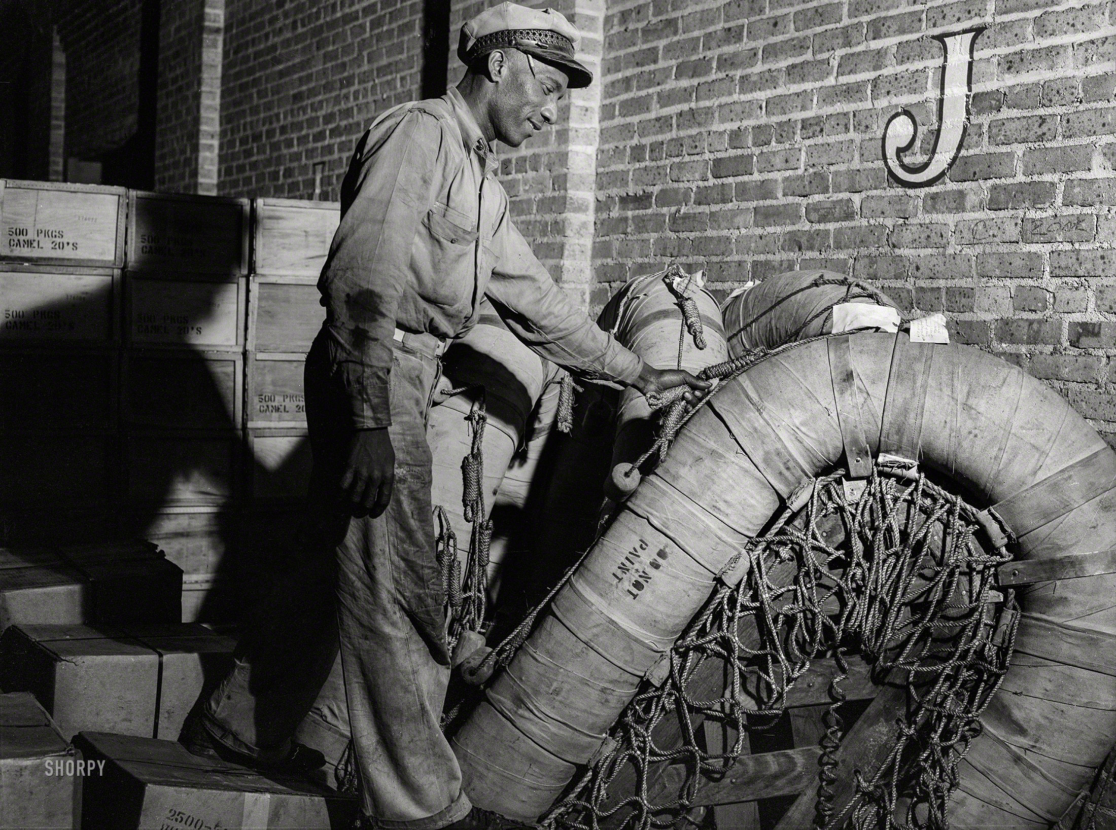 March 1943. "New Orleans, Louisiana. Loading a rubber raft onto a truck at the terminal of Associated Transport Company." Medium format negative by John Vachon for the Office of War Information. View full size.