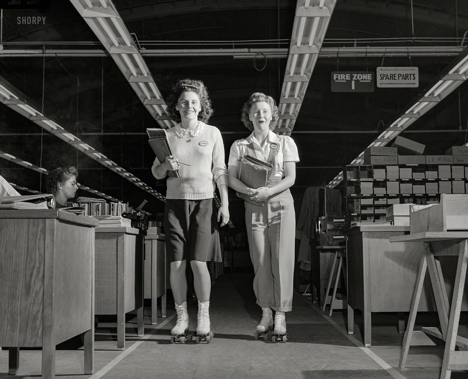 February 1943. "Girls on wheels expedite aircraft production. Literally helping to speed the war effort, Dolores Richardson and Geneva Carpenter are 'expeditors' at Douglas Aircraft in El Segundo, California, where they deliver inter-departmental messages on roller skates." Medium format acetate negative by Ann Rosener for the Office of War Information. View full size.