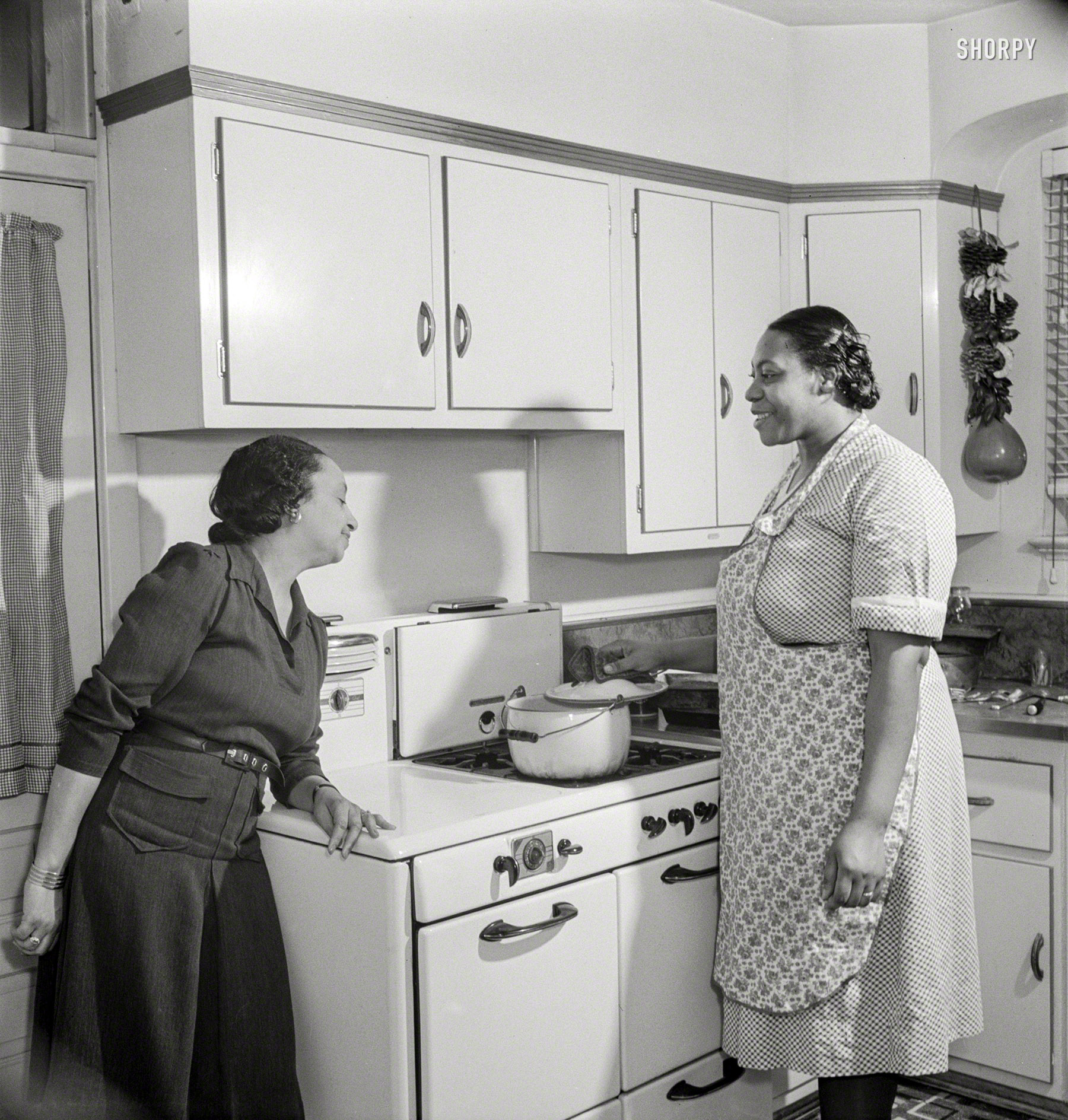 March 1942. Washington, D.C. "Teacher supervises the cooking of dinner by her maid. Negro home on the outskirts of the city which is owned by a doctor whose wife teaches in a Negro grammar school." Medium format nitrate negative by Marjory Collins for the Office of War Information. View full size.