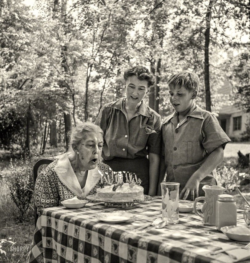 June 1942. Greenbelt, Maryland. "Grandma Taylor blows out the candles on her 83rd birthday cake while her daughter, Mrs. McCarl, and grandson look on." Photo by Marjory Collins for the Office of War Information. View full size.

