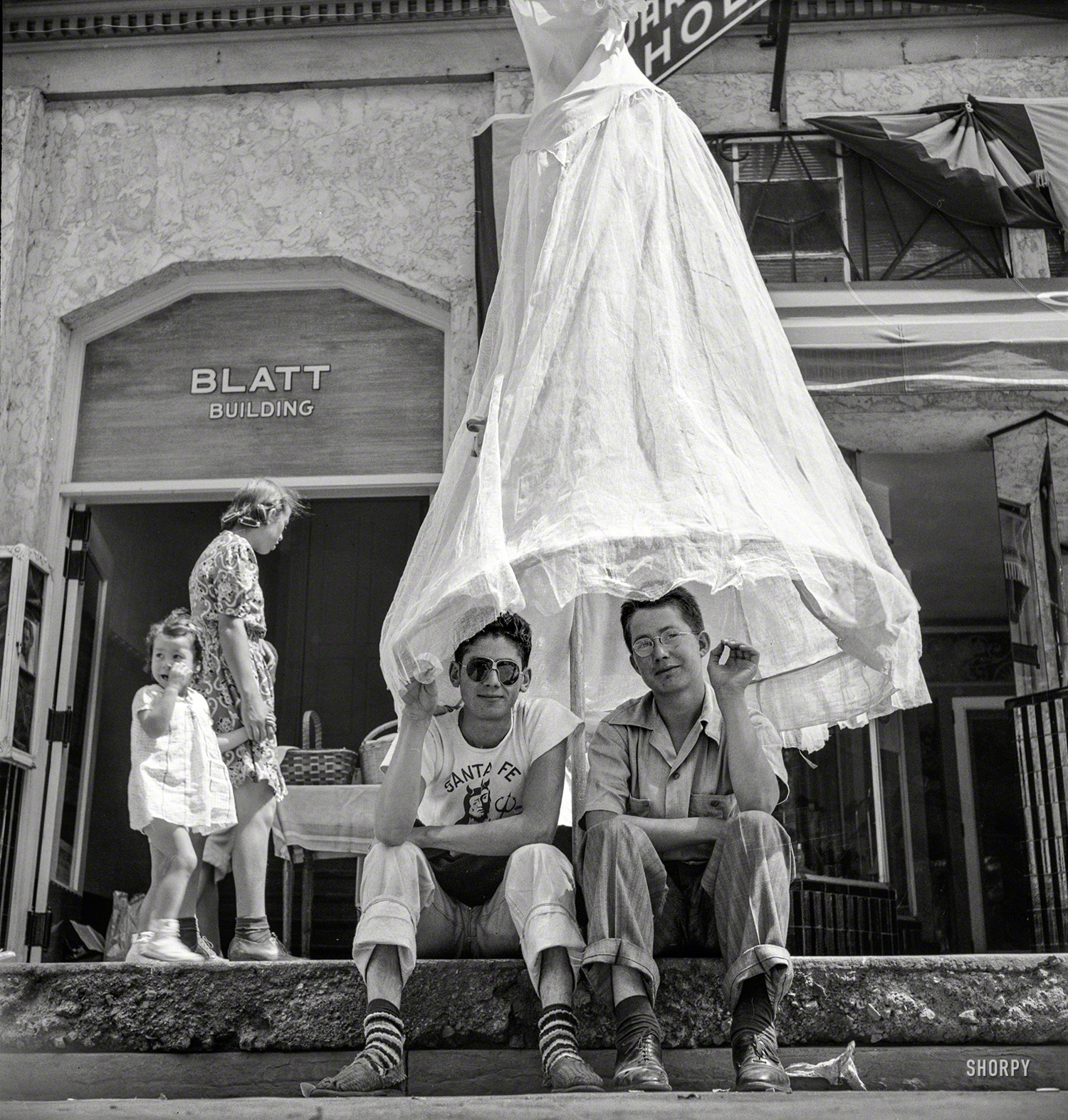 July 1940. "Street scene at the fiesta in Santa Fe, New Mexico." Our third look at the festive goings-on here, and we'll let someone else explain the skirt-brella. Photo by Russell Lee for the Farm Security Administration. View full size.