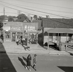 February 1943. "Daytona Beach, Fla. Sunday morning street scene in Midway. McGill's Fish Market and Fann Lunchroom, Pine Street and 2nd Avenue." Midway, along with Newtown and Waycross, comprised the "Negro quarters" of Daytona Beach. Photo by Gordon Parks, Office of War Information. View full size.