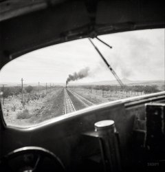 March 1943. "Ash Fork, Arizona (vicinity). Passing an eastbound freight on the Atchison, Topeka &amp; Santa Fe Railroad between Winslow and Seligman." Medium-format negative by Jack Delano, Office of War Information. View full size.
Rules of the roadWhat are the rules for multiple tracks -- don't we operate on the right hand side as with vehicular traffic? If the "smoking" engine is eastbound, these trains are operating on the "left" side of the road.
[Whether the engine is going east, west, or to the North Pole, they're driving on the left. Traffic could move in both directions on either track. Which might diverge and take you to entirely different destinations.  -Dave]
Left-handedMuch of the Santa Fe across Arizona and New Mexico was operated "left-handed".  For those who are really interested in why, this article explains it.
Somewhere in the distance . . .. . . you can still hear the train whistle.
This is as close as I could get so far. It is just west of Ash Fork and you can see the same peak in the distance. The rail line may have moved.
View Larger Map
(The Gallery, Jack Delano, Railroads)