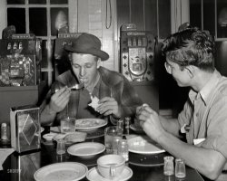 March 1943. "Pearlington, Mississippi. Truck drivers at a coffee stop on U.S. Highway 90." Photo by John Vachon, Office of War Information. View full size.
Nickel betsDon't know about the meal, but I'd love to have any one of those old, mechanical, one-arm bandits!  They may have been crooked, but they were pretty pieces of machinery.
Reminds me of Paul NewmanThe fellow with the fork to his mouth looks a lot like Paul Newman in Hud or Butch Cassidy and the Sundance Kid. Or maybe it's just the hat.
RE: REAL coffee creamer!Indeed noelani, perhaps some of them would have been appalled, but then again I remember having seen more than a few articles, newsreels, cartoons, and such from this time period touting the postwar world of the future where people would no longer have to toil at menial tasks like harvesting grain and milking cows (or brewing coffee for yourself), and that science and technology would rid us of the need to bother ourselves with food preparation, or concern ourselves with things like crop pests and drought.  So in fact, I think might be equally likely that time travelers from this period to ours would be more dumbfounded at our modern obsessions such as “sustainable organic” and “farm to table”!
Police protection neededPearlington is west of Gulfport, my childhood home. In 1955 a 2nd grade classmate was the son of a local policeman. I remember looking through the window of their garage and seeing a row of slot machines much like the ones in this photo, though they were 25 cent slots. I had never seen so many shiny quarters. I guess my friend's dad was keeping them out of the hands of malefactors.
The little decantersI agree that some of the little bottles were cream, but what about the ones that looked full of powder?  Sugar?
Highway 90: The jobs are gone . . .Highway 90 ran from Jacksonville, Florida, to West Texas.
Can't hear the name now without thinking of Nanci Griffith's "Gulf Coast Highway," a song worth a listen.
Hand me my salts!The glass salt shakers with the bumpy cross-hatching have been around forever. My mother and grandmother each had one, and the shaker I bought in college sits on my kitchen table now. The design is at least 75 years old, and still in production!
Look out behind you!One armed bandits!
Slot MachinesI just wish I owned one of those slot machines in the background. Today they're worth a small fortune!
REAL coffee creamer!It doesn't look like those men drank their coffee black!  Look at those little cream bottles!  Maybe it was half and half, and not heavy cream, but you can bet that it actually came from a cow, unlike what we get, these days!  I think if people from WWII era and before could see what we eat, now, they would be appalled at all of the non-food that we eat.  I think they'd also be appalled by the way that coffee has become something many people don't make for themselves, but spend $8 a day to have made for them (with more artificial ingredients added).  
Post-script to KINES:
You may be correct about a certain section of society, but not everybody.  My grandfather, who was in his 30s when the picture was taken, was a dairy farmer, at the time.  I'm sure he probably dreamed of something less demanding than milk a bunch of cows, by hand, every morning and evening. However, he was still around in the 90s, and he WAS appalled at some of what was passing for food!  I think he, and many others, would have appreciated some of the new technology that would have shortened his work day, considerably, but he would still have wanted to have REAL food, for his labors.  The only people I can imagine who would not also want that would be those born too late to have a chance to get to know what food was for millennia before they were born.
(The Gallery, Eateries & Bars, John Vachon)