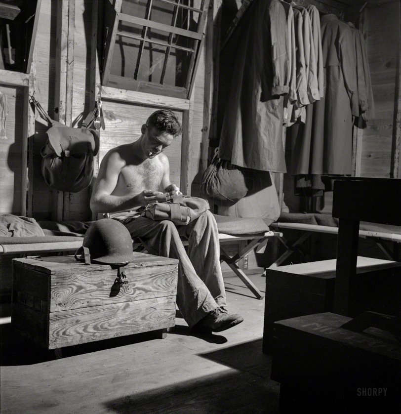 July 1943. Greenville, South Carolina. "Air Service Command. Enlisted man folding up his gas mask to hang on the wall after having worn it all day." Medium-format negative by Jack Delano for the Office of War Information. View full size.
