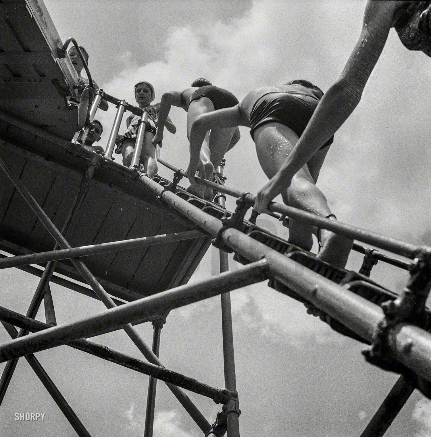 July 1943. Glen Echo, Maryland. "Climbing the ladder to the sliding board at the Glen Echo swimming pool on a hot day." Photo by Esther Bubley. View full size.