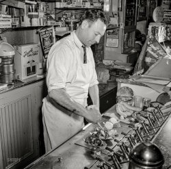 May 1942. Southington, Conn. "Dimitrios Giorgios, who came from Greece, runs a soda fountain. He wasn't here long before the country entered World War I and he joined up. A member of the American Legion, he is shown here making banana splits." Photo by Fenno Jacobs, Office of War Information. View full size.