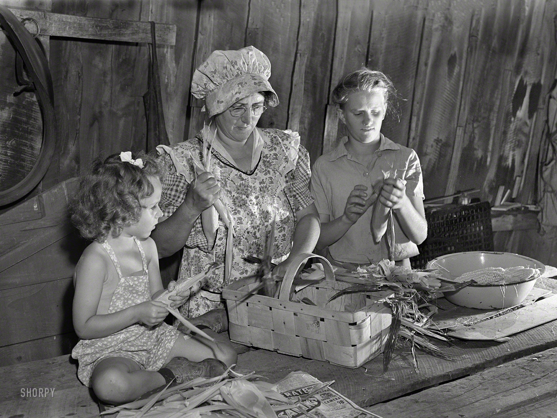 Sept. 1942. Canfield, Ohio. "Mrs. Harry Mercer, a young neighbor and grandchild, husking and removing silk from the corn. The corn will be dried and stored for later use." Photo by Ann Rosener, Office of War Information. View full size.