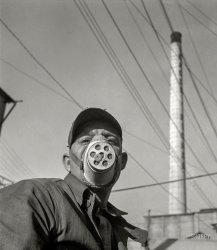 January 1943. "The operator of a zinc ore loader at a large smelting plant is protected against harmful dust by a mask. From the Eagle-Picher plant near Cardin, Oklahoma, come great quantities of zinc and lead to serve many important purposes in the war effort." 4x5 inch nitrate negative by Fritz Henle for the Office of War Information. View full size.