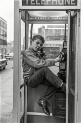 "Boy in telephone booth, Boston, 1963." Engaged in the archaic activity known as dialing a pay phone, as well as demonstrating the esoteric skill of booth-wedging. 35mm negative, photographer unknown. View full size.