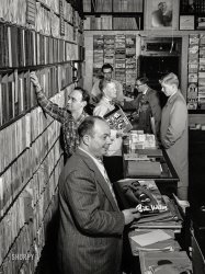 August 1947. New York. "Lou Blum, Jack Crystal [reaching] and Herbie Hill [rear] at Milt Gabler's Commodore Record Shop on 42nd Street." Medium format negative by William Gottlieb for Down Beat magazine. View full size.