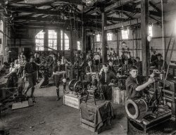 Sept. 26, 1916. "Boys of Wanganui Technical College, New Zealand, during an engineering class." Tesla Studios glass negative. View full size.
An OSHA NightmareBut I would have loved a class like that!
No OSHA equivalent in 1916 New ZealandThey sure as heck wouldn't have let us work with spinning machines, while wearing ties that could have gotten caught in them, in my shop class. And not one protective eye goggle anywhere.
TiesMy first thought was "surely Shorpy comments won't state the obvious concerning ties and machinery."
[Let's not forget OSHA. - Dave]
Hello OSHA, here&#039;s what happenedA room of moving and spinning equipment and all those neckties.
RubberneckersEgads! I wonder how many boys were injured before they discovered that ties and moving machinery don't mix?
The machinery (and ties a bit)That is a pretty complete set of machine tools in there, I am particularly impressed by the set of gears that go with the metal lathe near the center. The boy in the front is holding a mill file, probably they taught proper draw-filing technique for creating flat and true surfaces.
The ties no doubt indicate their class standing and, since this is a posed picture, are probably tucked into their shirts when actually working with the equipment.
At First GlanceI thought I was seeing a Lewis Hine scene of downtrodden young boys, but as soon as I saw the neckwear I knew it wasn't going to be that bad.
Damn the hazards!When our shift ends, we're off to camp!
Changing timesThere is so much to look at here, besides the frightening neckties. The pyramidal change gear stands are neat for sure. Also notice the two marine engines in the right foreground. The taller single cylinder engine on the metal stand is one of those new-fangled internal combustion models, but just behind and to the right you see a classic double expansion steam launch engine perched on a crate.
It&#039;s a digital worldTime for the photograph, boys.  Everyone with ten fingers, move to the front.
Too young?Aren't some of these kids too young to be in a Technical College or is this just a substitute for a trade high school?
I had a class like that.I went to Stuyvesant High School in New York and we had a wood shop with all the overhead belts and pulleys. They powered lathes, joiners, planers, grinders, etc. I can still hear the noise of the electric motor that drove them and I can still smell the wood. We did NOT wear ties.
Not mentioning tiesAre they making appliances?
Hooks! We need hooks!Where are we to hang our coats?
Beneath it all...Is a wood-block floor.
I never understood why they were used; perhaps in a 'light' industrial environment they were more economical and durable than concrete (or iron-infused concrete).
The Wood Bock FloorsI have no idea if they are still used but when I retired in 1994 the large company I worked for who has many factories around Illinois used those creosote soaked wooden blocks over concrete.
Crews were constantly replacing bad blocks. From what I remember they absorbed falling metal parts so they weren't damaged and were easier on a person standing eight hours a day. I'm sure often moving machinery to new locations also had something to do with it.
I didn't have a job where I had to stand nearly that long. But personally my legs and feet ached from those blocks.
(Technology, The Gallery, Education, Schools, New Zealand)