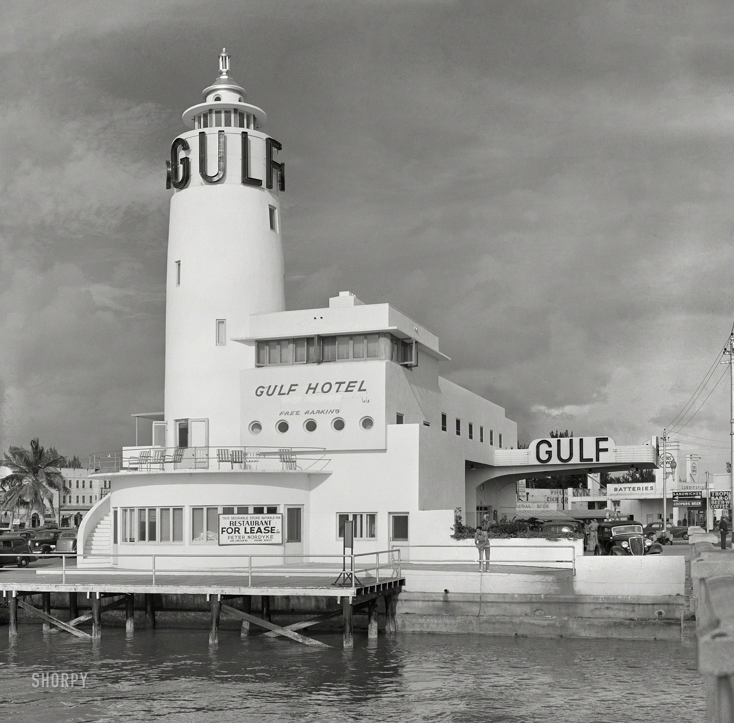 &nbsp; &nbsp; &nbsp; &nbsp; The Gulf Hotel building (and lighthouse) at 1315 Fifth Street.
April 1939. "Even the gas stations in Miami Beach are on an elaborate scale, often modern design, resembling hotels." Composite of two photos by Marion Post Wolcott for the Farm Security Administration. View full size.