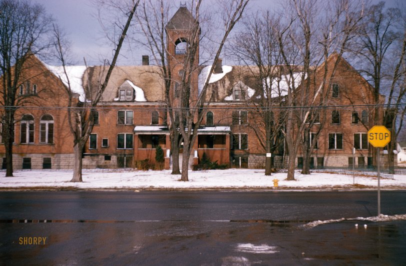 From somewhere in (probably) Wisconsin (maybe Menomonie), sometime in the 1950s, comes this unlabeled Kodachrome slide of what might be an old school or church building, but who can say? For traffic control we have a yellow stop sign with cat-eye reflectors. View full size.