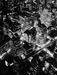 New York circa 1932. "Night view, Manhattan." Photo by Berenice Abbott (1898- 1991). Library of Congress Prints &amp; Photographs Collection. View full size.
Digital Empirethanks google
What wonderful pictureBernice Abbott took this picture from atop the newly built Empire State Building looking toward the northwest. The two streets are Sixth Avenue (with the elevated train tracks) and Broadway. 
Christmas Jewel BoxOne of the most beautiful sights I can remember was flying into New York City shortly before Christmas on an extremely clear, cold, dark night some years ago.  Preparing for landing we flew low over the city as spread out below us was a seemingly  endless carpet of brilliantly colored rubies, sapphires, emeralds, diamonds and gold that was reminiscent of a pirate's treasure chest or an imaginary  kaleidoscope out of a fantasy, twinkling, enchanting and alluring. If this photo of the city lights was in jewel-tone colors, you would get an idea of just how inviting and unforgettable it looked.
The Naked CityTen thousand stories down there folks, each amenable to exposition and solution in one hour, less commercial breaks.
Old Metropolitan Opera HouseJust beyond the distinctive tower of the Lefcourt Normandie Building (right of center and toward the top of the photo) is the gabled stage area of the old Metropolitan Opera House.  The auditorium fronted at 1411 Broadway, but extended through the block to 7th Avenue.  The old Met opened in 1883, but was gutted by fire in 1892.  Rebuilt to match the original, it served until 1966 when the Metropolitan Opera was relocated to Lincoln Center.  The building was demolished in 1967. 
The Sixth Avenue ElAt the time of this photo the Sixth Avenue El was already under a metaphorical death sentence.  The IND subway under Sixth was either in the last phases of planning or the early stages of actual construction, and everyone understood that the El would be demolished once the subway was ready.  That happened near the end of the 1930's. 
Demolition of the Sixth Avenue El was not a tragedy like that of its counterpart on Third Avenue a decade and a half later.  There was, obvious, a subway replacement on Sixth, while the Second Avenue subway that was meant to replace the Third Avenue El resembles the offspring of a mythological creature and a sick joke.  Sixth Avenue also was a much busier thoroughfare than Third and therefore a less appropriate location for having elevated trains clattering overhead.  
A persistent urban legend holds that scrap steel from the Sixth Avenue El was sold to Japanese dealers in 1939 and 1940 and used to build weapons that within a few years would be used against American troops.  Given that scrap steel is a more or less fungible commodity there's no way of proving or disproving this rumor.
WistfulThat city's largely gone, unfortunately; especially in the downtown area.  My opinion:  The lowly double-hung window influenced the very shape of some mighty fine architecture.  Put a few buildings like that together et, voilà.  Compare this scene with the landscape of monoliths a similar vantage point would likely reveal today.  I won't even mention the elevated train--whoops, I did.  Suddenly I long for the aroma of cigar smoke and leaded gas.
(NYC)