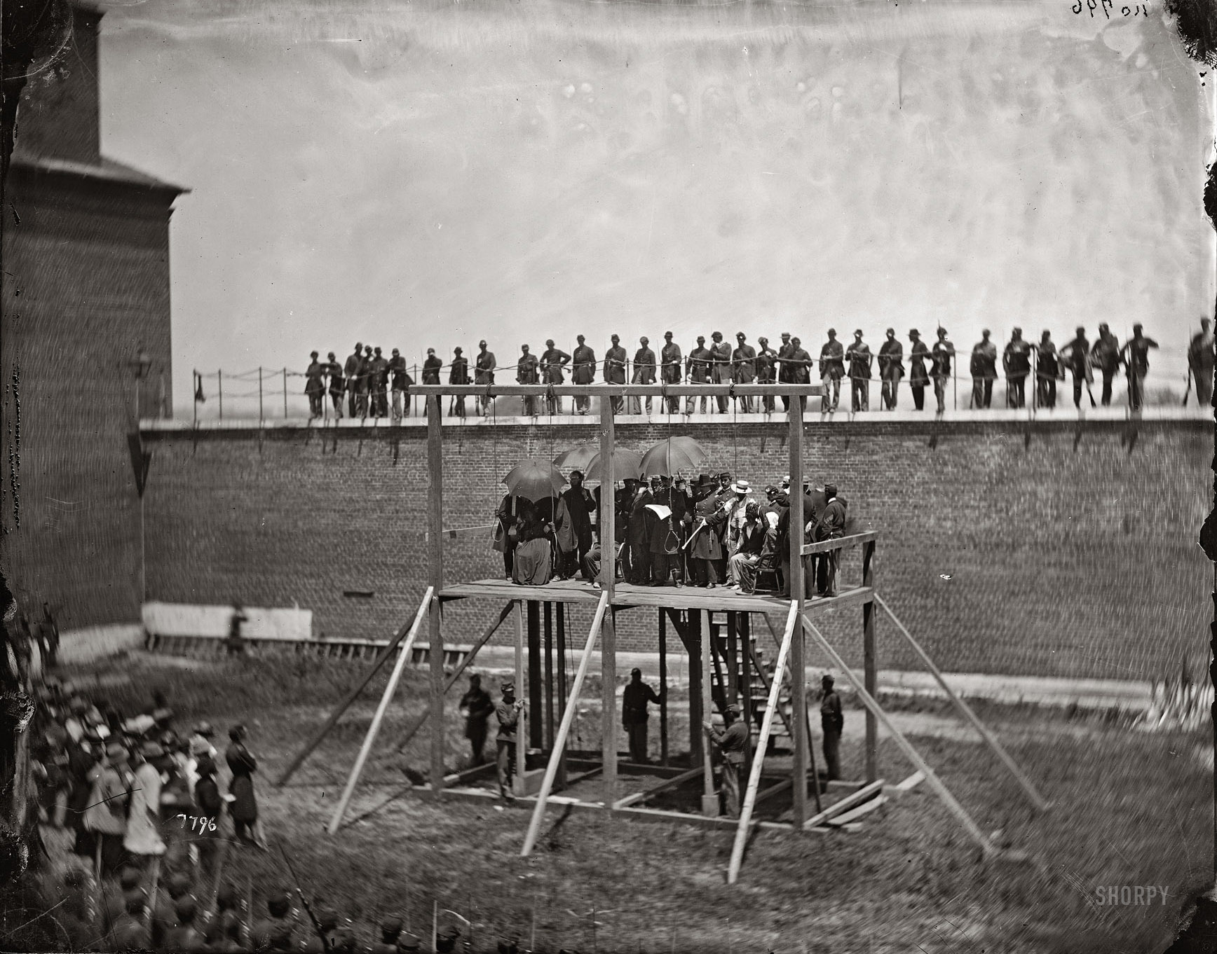 Gen. John F. Hartranft reading the death warrant to the four condemned Lincoln assassination conspirators (Mrs. Surratt, Payne, Herold, Atzerodt) on the scaffold at Fort McNair, Washington. July 7, 1865. View full size. Photograph by Alexander Gardner. More execution photos at GhostCowboy.