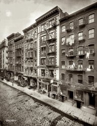Another view of Mott Street in New York's Little Italy (now Chinatown) circa 1910. The building in the middle, 156 Mott, with the Italian pharmacy, is now the Foot Reflexology Center in this Google Street View. The address on the right, 156 Mott, is now just two stories. Most of the basement entrances have been covered. 8x10 glass negative, George Grantham Bain Collection. View full size.