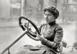 At the wheel circa 1915. "NO CAPTION" is the caption here. Perhaps someone will recognize the insignia on the lady's uniform. Harris &amp; Ewing Collection glass negative. View full size.
Joan Newton CuneoThe picture is of Mrs. Joan Newton Cuneo, sitting behind the wheel of her race car, a 1908 Knox Giant and dressed in a smartly styled driving suit. It appeared in the April 1910 issue of The Outing Magazine.
Mrs. Cuneo was a socialite who purchased her first car - a steamer - and spent the next year mastering the art of driving, whereupon she bought a new White steamer.  In 1905 she bought yet another new White and entered the Glidden Tour. By fall she was performing fast exhibition driving at Atlantic City and at the Fair in Poughkeepsie, where she ran against Barney Oldfield and set the women's record for the flying mile at 1 minute and 24 seconds.
She bought her first gasoline-powered car in 1907 and continued participating in tour contests; by 1908 she was completing tours with perfect scores and for the Women's Motoring Club run to Philadelphia and back, the Lancia factory asked her to drive their famous Lancia Lampo. Other manufacturers began asking that she race in their vehicles, and she eventually settled on the big Knox Giant racer.  In early 1909 she ran this car to numerous victories at the New Orleans Mardi Gras celebration, at one point even beating the famous Ralph De Palma.  She was named the National Amateur Champion and claimed five trophys.
Not long after her stunning victories in New Orleans, and despite the fact that Mrs. Cuneo had been a member of theirs since 1905, the American Automobile Association (the organization that sponsored most of the big events) banned not just women drivers from their events, but women passengers as well.  Many writers of the day felt it was because too many men drivers would stay away if they were consistently beaten by a woman.  Joan Cuneo did not protest; she just more or less retired from racing.  She bought a duplicate of the Knox Giant from the factory and continued to run non-AAA sponsored tours, and setting track records in exhibitions.  In the March 1908 issue of Country Life in America she wrote an article titled "Why There Are So Few Women Automobilists" that is still quoted today in histories of early woman drivers.
Possibly only one (two) comments here:Vrooom ! Vrooom !
Crossed flagsSignal Corps.  Women were used to fill positions, did not serve overseas.
Lots of Buttonsbut no Bows.
Tanks a LotHow big were the gas tanks on those cars, anyway? They look to be about the size of a 55 gallon oil drum.
Signal CorpsAs a boy, I polished my father's Signal Corps insignia enough to know them on sight.
Fast WomanShe also became the fastest woman with a speed of 111.5 mph on the Long Island Motor Parkway while driving a Pope Hummer on April 17, 1911.  This was over 1/2 a mile.
She had her own song.
     O Mrs. Cuneo, O Mrs. Cuneo,
     The greatest woman driver that we know,
     She keeps a-going, she makes a showing,
     Does Mrs. Cuney-uney-uney-O
There is a article about her here with additional details of her career and three more pictures in addition to the one below.
Her Knox and a Pope Hummer are pictured below.  Note: Comment corrected for photo that did not attach.
http://dvalnews.com/view/full_story/7418695/article-Those-daring-young--...
Two Knox, no PopeBoth pictures below are of the Knox Giant&mdash;you can spot the Knox emblem on the radiator in the top picture.


Here's a photo of the Pope-Hartford, nicknamed the Hummer (no chain drive):

(The Gallery, Cars, Trucks, Buses, D.C., Harris + Ewing)