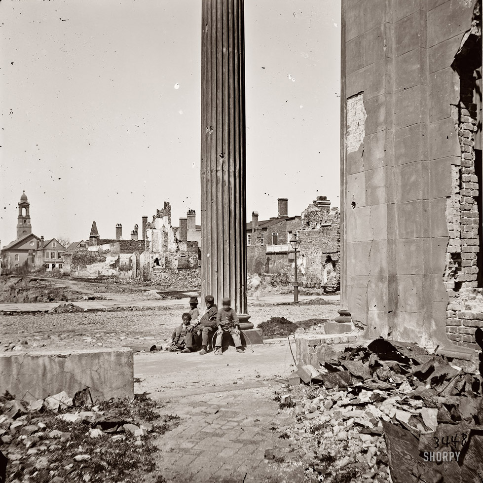 View of ruined buildings through porch of the Circular Church at 150 Meeting Street, Charleston, South Carolina. April 1865. View full size. Wet collodion glass plate, half of stereograph pair. Photographer unknown. While much of the damage shown here is from shelling by the Federal Navy, the Circular Church itself was heavily damaged by fire in 1861. Alternate view.