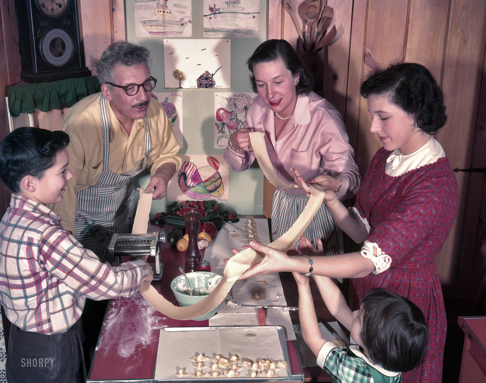 1955. "Opera singer Ezio Pinza and his wife Doris at home cooking a family meal with their children; the family enjoying a candlelit meal in their dining room. Includes the family making pasta." Photos by Kenneth Eide for the Look magazine article "Ezio Pinza's Old-Country Food Goes American." View full size.