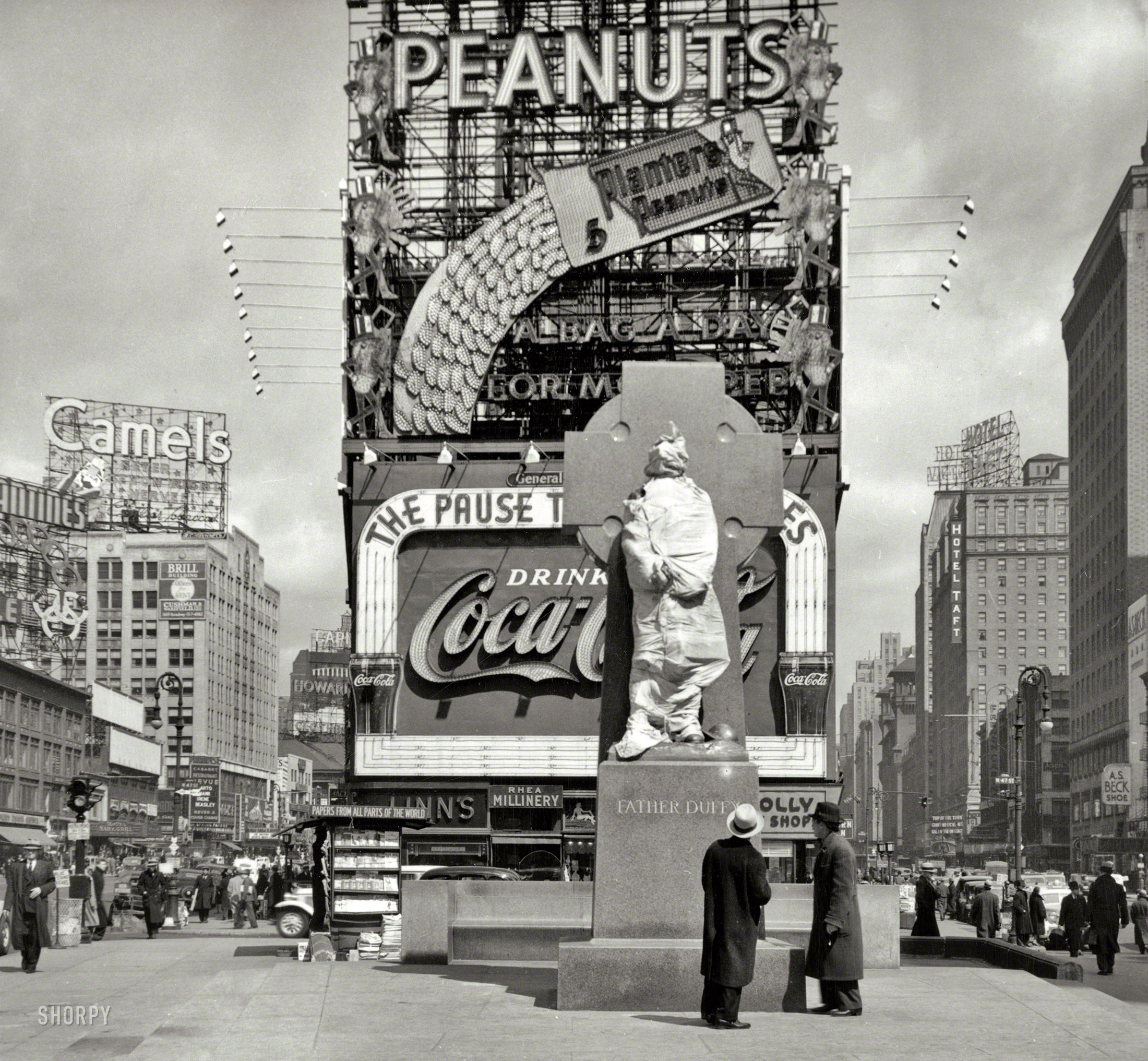 New York, 1937. "Times Square with Father Duffy statue still wrapped up." Sculptor Charles Keck's likeness of Francis P. Duffy, the New York Army National Guard chaplain decorated for his service in France with the 69th Infantry Regiment during World War I. Duffy Square and the statue were dedicated on May 2, 1937, by Mayor LaGuardia. Photo by Peter Sekaer. View full size.