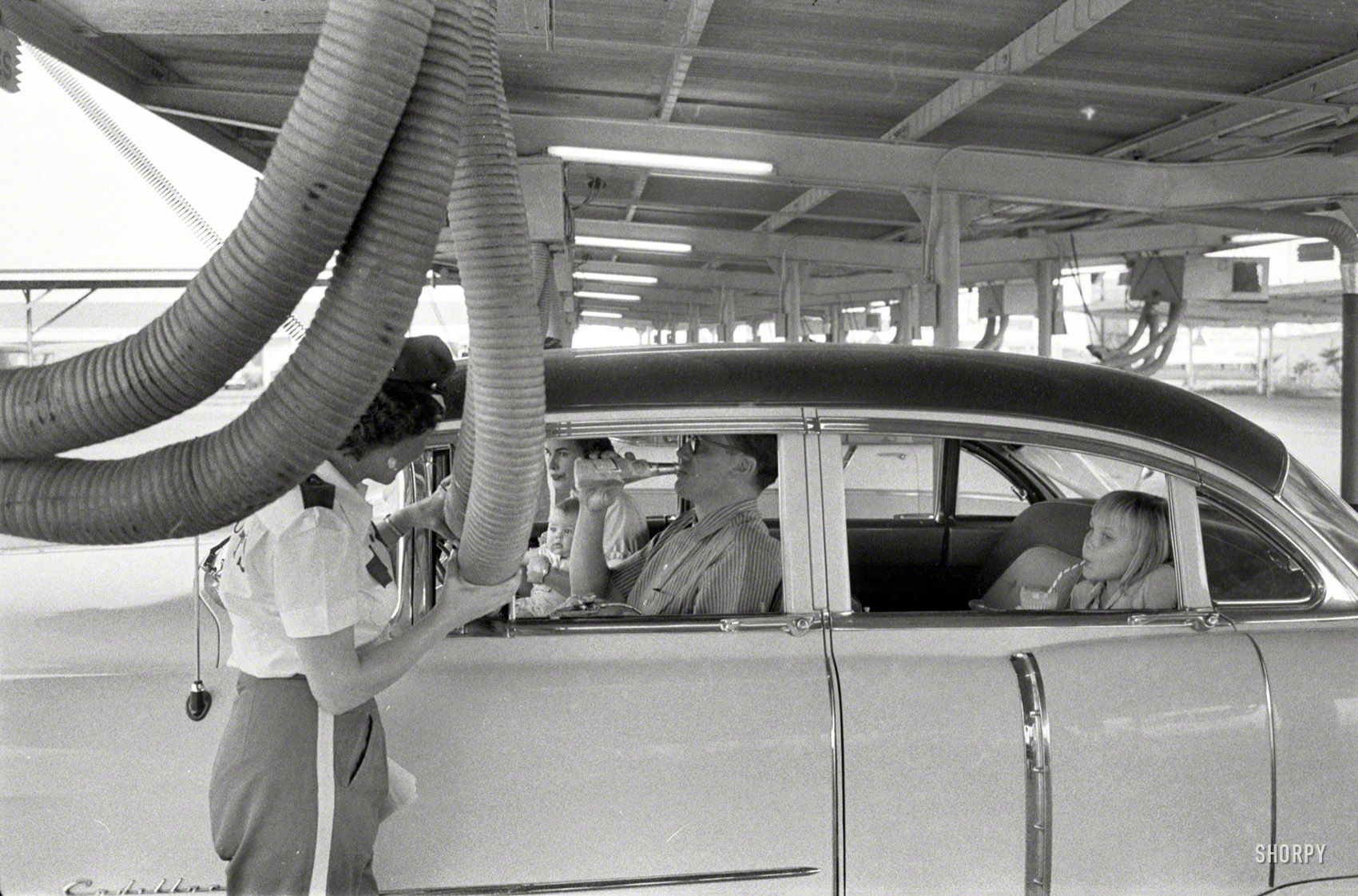 1957. "Robert and Norma Norton of Houston, Texas, with their family, illustrating life before and after having the house air-conditioned. Includes photos of the family at a drive-in restaurant having cool air piped into their car" -- a Cadillac sedan that already has air conditioning. Photo by Jim Hansen for the Look magazine article "How the Nortons Beat the Heat." View full size.