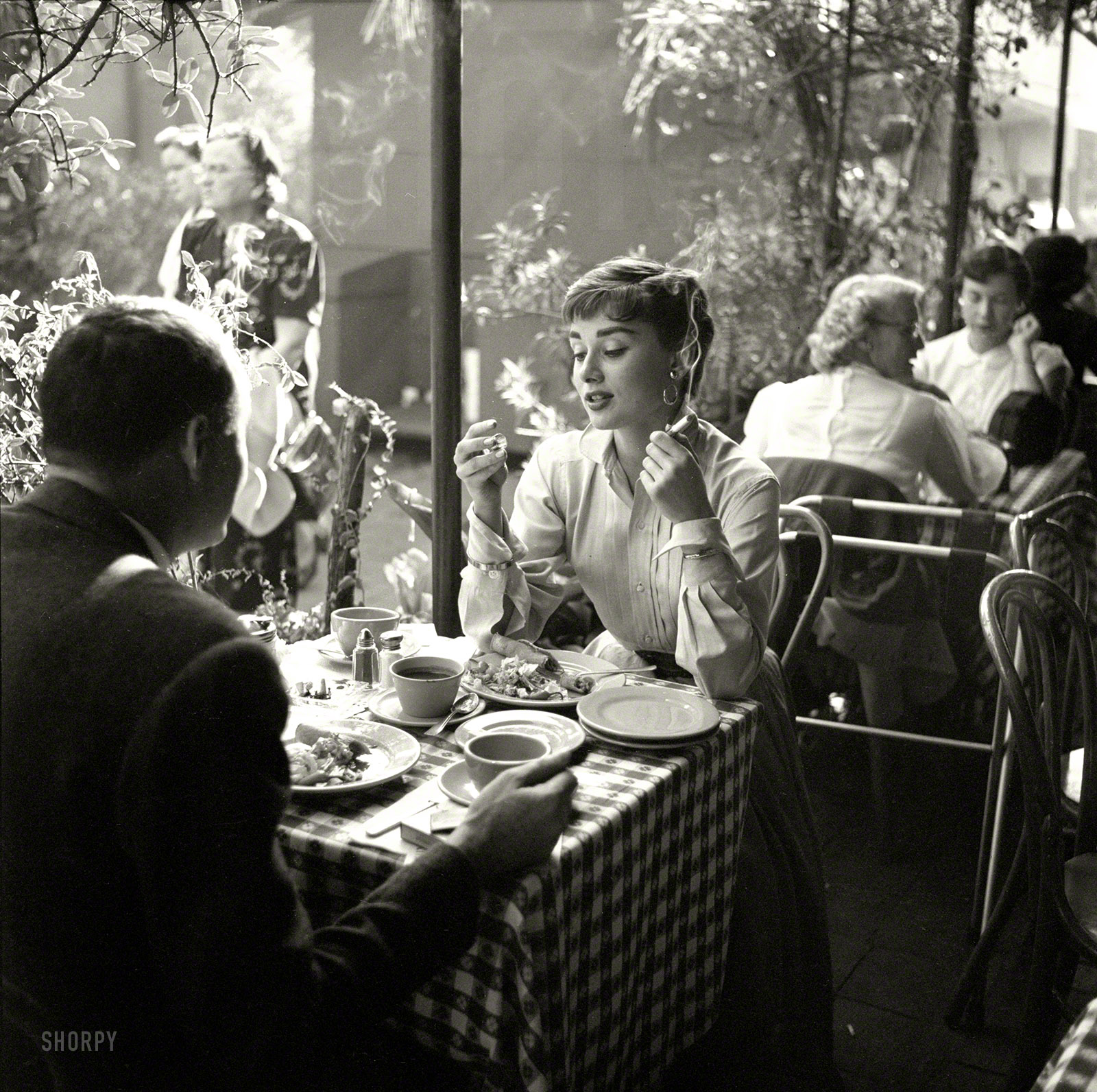 Circa 1953. "Actress Audrey Hepburn with dining companion in Mexico." From photos by Earl Theisen for Look magazine. View full size.