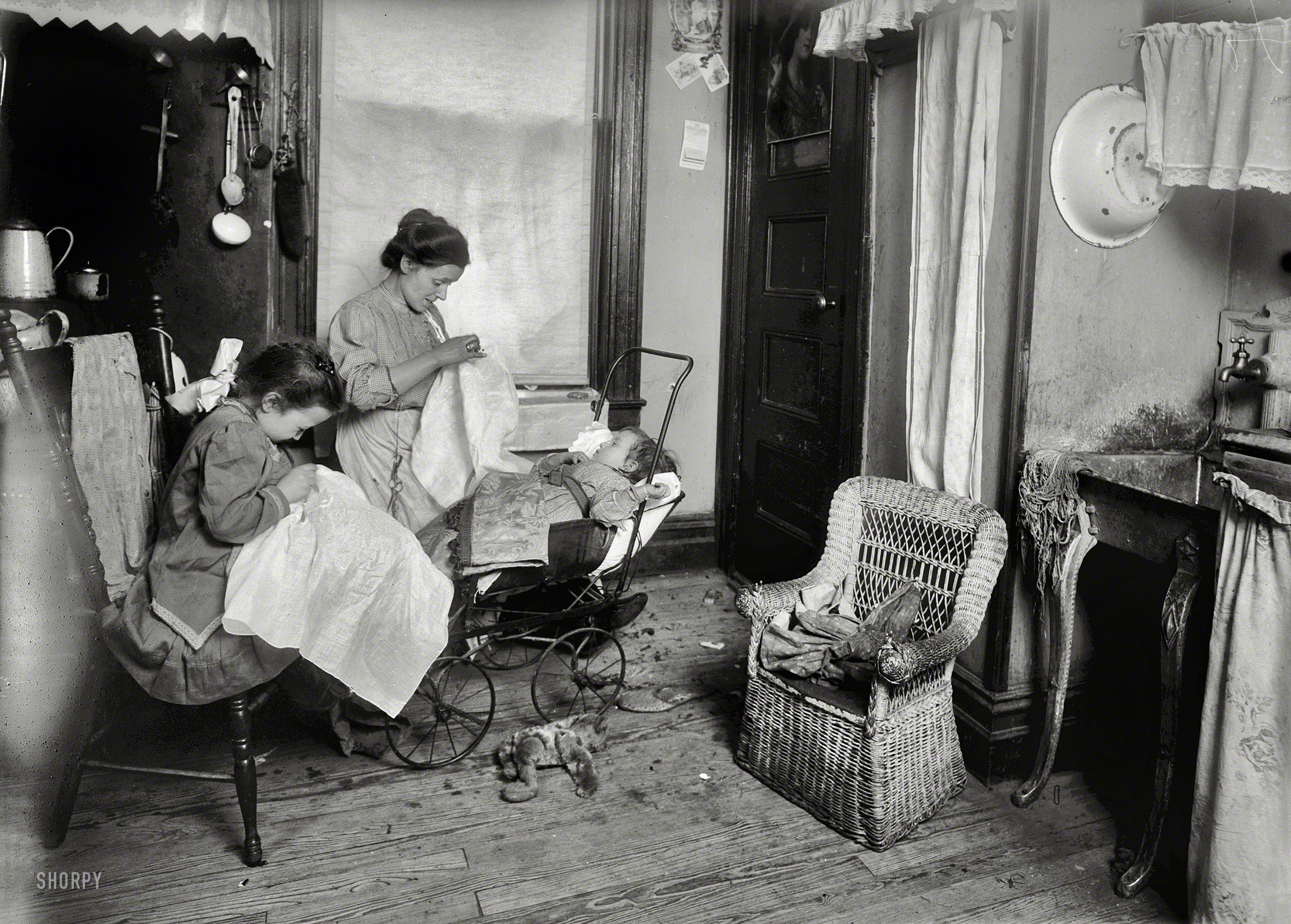 January 1912. "Tenement homework, New York, 309 W. 146th Street. Mrs. De Levo [?] and her 7-year-old daughter, Lorenza, embroidering ladies' waists in their dirty kitchen-living room. Lorenza makes the stems of the flowers. Her mother said, 'See how smart she is. I show her how and right away she makes them. She is so little because she's been sick so much.' She works after school. Father is out of a job. 'They pay too cheap for lace.' Said they make about $2 a week." Glass nega&shy;tive by Lewis Wickes Hine for the National Child Labor Committee. View full size.