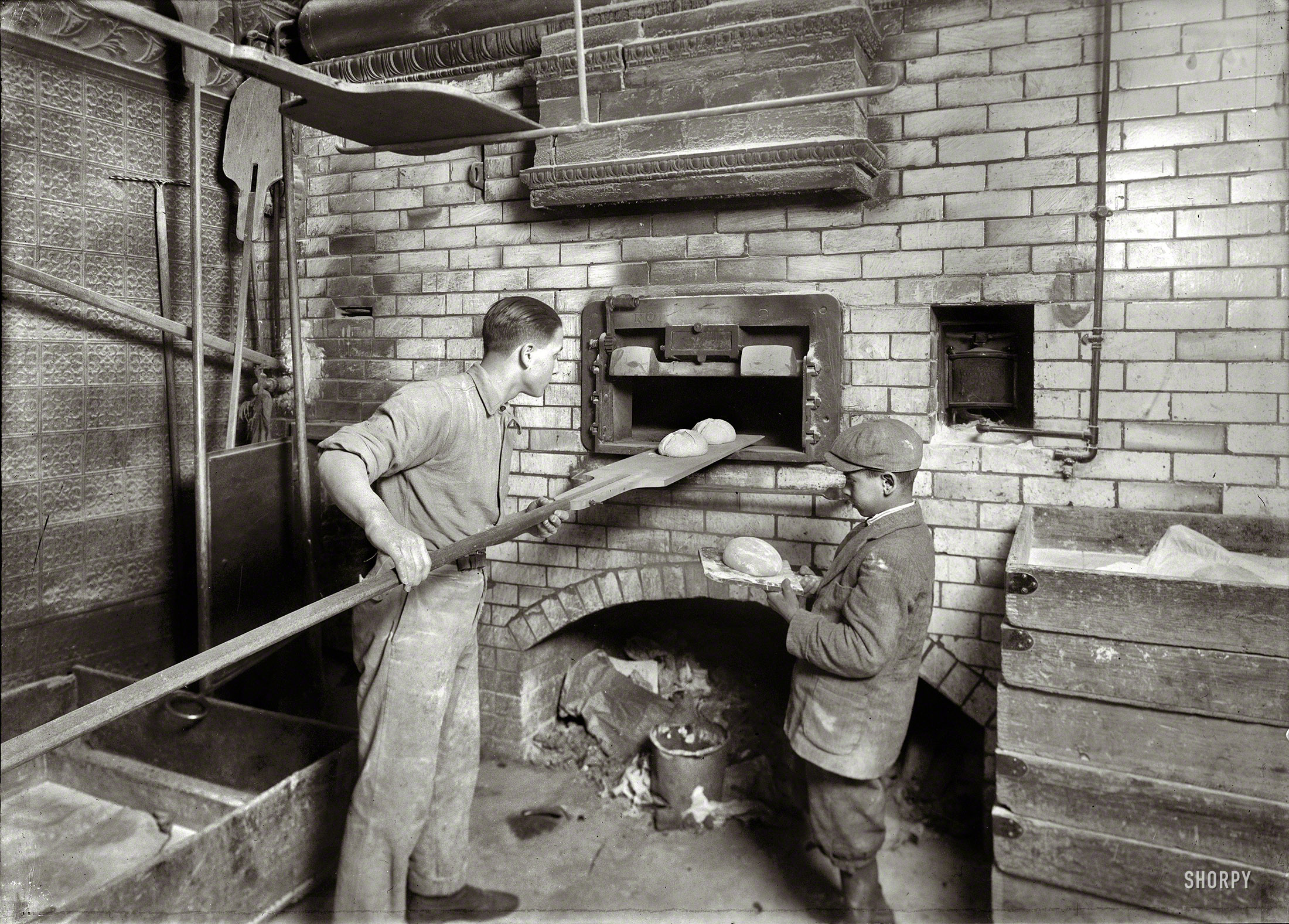 Feb. 1, 1917. Cambridge, Mass. "Vincenzo Messina, 15 years old and brother Angelo, 11, baking bread for father, 174 Salem Street. Vincenzo is working nights now, from 5 p.m. to 5 a.m. Usually works on day shift. Angelo helps a great deal, tends store and helps bake, too." Photo by Lewis Wickes Hine. View full size.