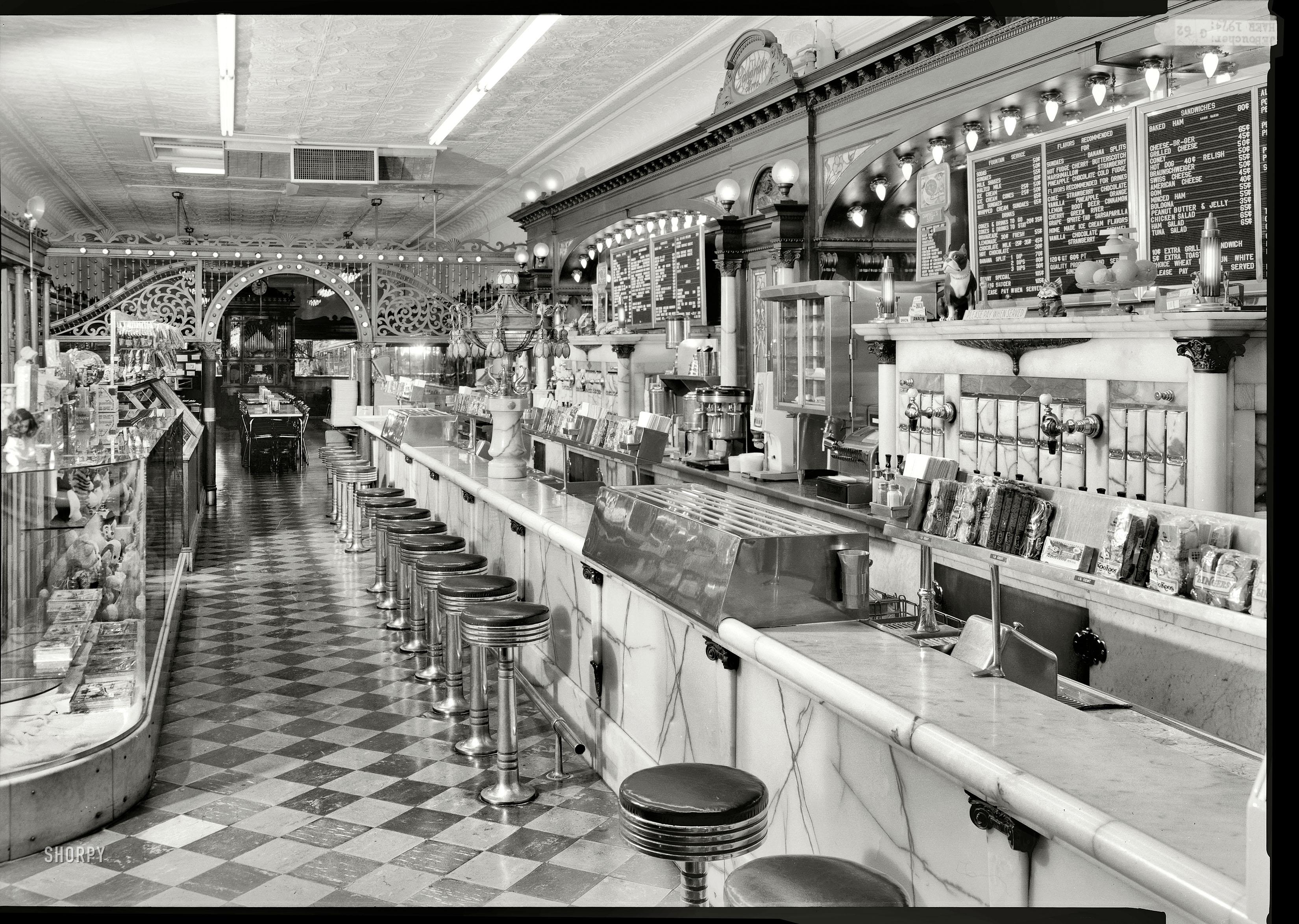 April 1974. Columbus, Indiana. "General view of soda fountain area -- Zaharako Bros. Ice Cream Parlor, 329 Washington Street. Family-run ice cream and confectionery business operating since 1900. This parlor was a major social center in Columbus for the first 50 years. Known for its elaborate interior and ice cream still made by the Zaharako family. Mexican onyx soda fountains purchased 1905; extra counter added 1949; store front modernized 1959." 5x7 negative by Jack E. Boucher, Historic American Buildings Survey. View full size.