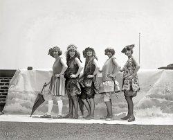 "Lansburgh Bathing Girls, 1922." Avert your eyes, gentlemen -- the leftmost lady's knees are showing. Next to her, Shorpy regulars will recognize Iola Swinnerton, winsome Washington beauty. National Photo glass negative. View full size.
It&#039;s hard to tellthey are not really at the ocean.
No shameNext thing you know they will be appearing at the beach without stockings. Where will it end?
Prop FlopWhat we have here is a failure to crop the brick wall out of the picture.
No gal could get past those &quot;bathing suits&quot;There's a pretty face or two in this picture but the outfits are so outlandishly awful (and unflattering to boot), it would take a veritable Angelina Jolie to shine in these get-ups. (clearly "less is more" was NOT the motto in those days for bathing beauties)
I&#039;m so sorry, butare the three on the right part of Les Cagelles?
Could you swim in those?All that cloth would probably be heavy when wet. I love the style, though.
Gakkk!I read an interview with the "oldest living Ziegfeld girl", Doris Eaton Travis from just before she died at age 106 last year.  She said she didn't like the fashions of the 1920's.  She thought they were unflattering.  And I have to say, these outfits are BIG TIME hideous.  I mean, the addition of color might help, but what this looks like to me is a VERY awkward halfway point between old fashioned "bathing costumes" and modern one piece swimsuits.  Gak indeed. 
25 yearsfrom here to the first bikini. Regarding these styles,I think the birth rate in the early '20s must have been near zero.
90 Years LaterIn a short 90 years, girls went from 95% coverage to only 5% coverage!
Roll &#039;em, girlies, roll &#039;em!When I was in middle school, in the early '80s, I took a judo class taught by one Morey Korey, who was then about 80 years old. He really moved well for an octogenarian, and naturally, he was big on stretching exercises, which were accompanied by a song he had learned as a teenager, and which he taught us:
Roll 'em, girlies, roll 'em,
Go ahead and roll 'em,
Go ahead and show your pretty knees.
Don't let teacher tell you that it's shocking.
Paint your sweetie's picture on your stocking.
Laugh at Ma, laugh at Pa,
Give them all the ha-ha-ha,
Roll 'em girlies, girlies roll your own!
Bathing Girls: the soundtrackGood memory, Lectrogeek. "Even grouchy traffic cops get jolly, when they see you step into a trolley." Here's Billy Murray's popular rendition of "Roll 'Em Girls," recorded on November 4, 1925.

Curtis &amp; LemmonA publicity still from Some Like It Hot?
No expense sparedBoy, that photographer really went all-out with the backdrop, and even if he managed to crop it well, that flagpole sticking out of the ocean behind the girl on the right is going to be harder to get rid of.
RealisticI get seasick every time I look at this.
20s attireI LOVE, LOVE the 20s fashions -- just NOT the  bathing attire!!
(The Gallery, D.C., Iola S., Natl Photo, Pretty Girls, Swimming)