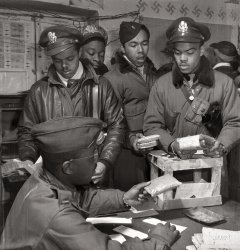March 1945. "Tuskegee Airmen series. 'Escape kits' (cyanide) being distributed to fighter pilots at air base in Ramitelli, Italy." Theodore G. Lumpkin Jr., seated, with (L-R): Joseph L. "Joe" Chineworth, Memphis, Class 44-E; Robert C. Robinson, Asheville, Class 44-G; Driskell B. Ponder, Chicago, 43-I; Robert W. Williams, Ottumwa, Iowa, 44-E. Gelatin silver print by Toni Frissell. View full size.